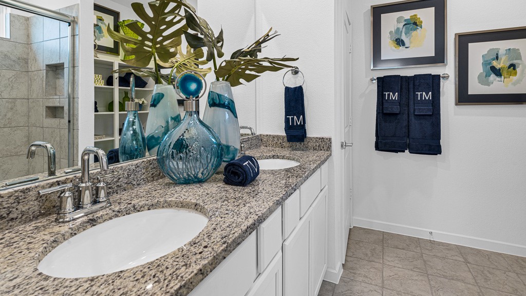 Primary ensuite bath has dual vanities with silver fixtures, modern white cabinetry, and recessed shelves for towels, storage and decor.