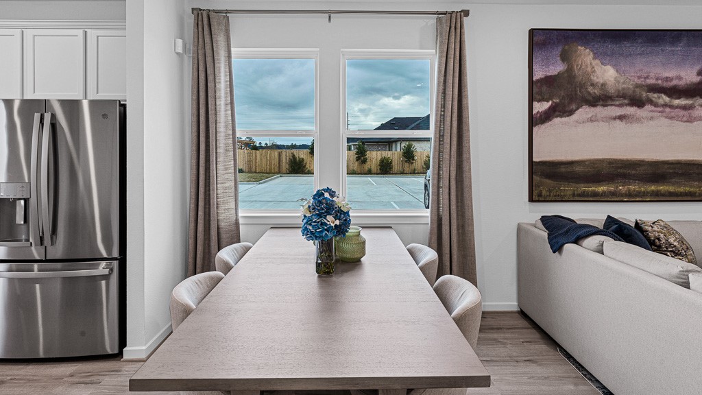 Dining room is open, yet quaint and intimate with large table butted against beautiful windows adorned with custom drapery.