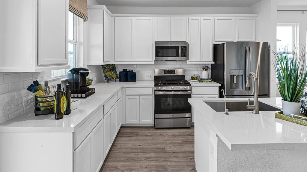Crisp white modern cabinetry looks fabulous with white quartz counters, subway tile backsplash for a seamless look, while wood floors add warmth, character, and texture.