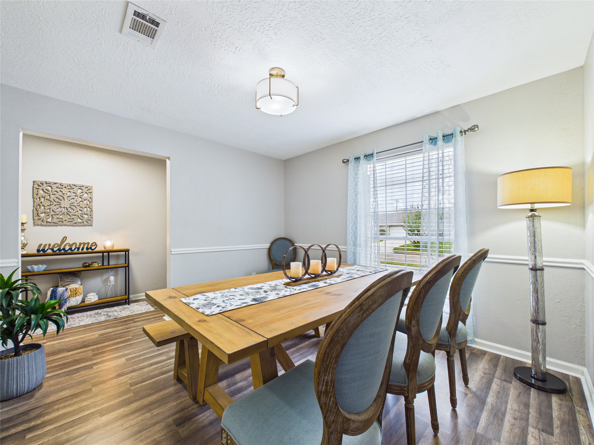 Bright dining area with elegant flooring, a large window for natural light, and a stylish chandelier. Bright dining area with elegant flooring, a large window for natural light, and a stylish chandelier.