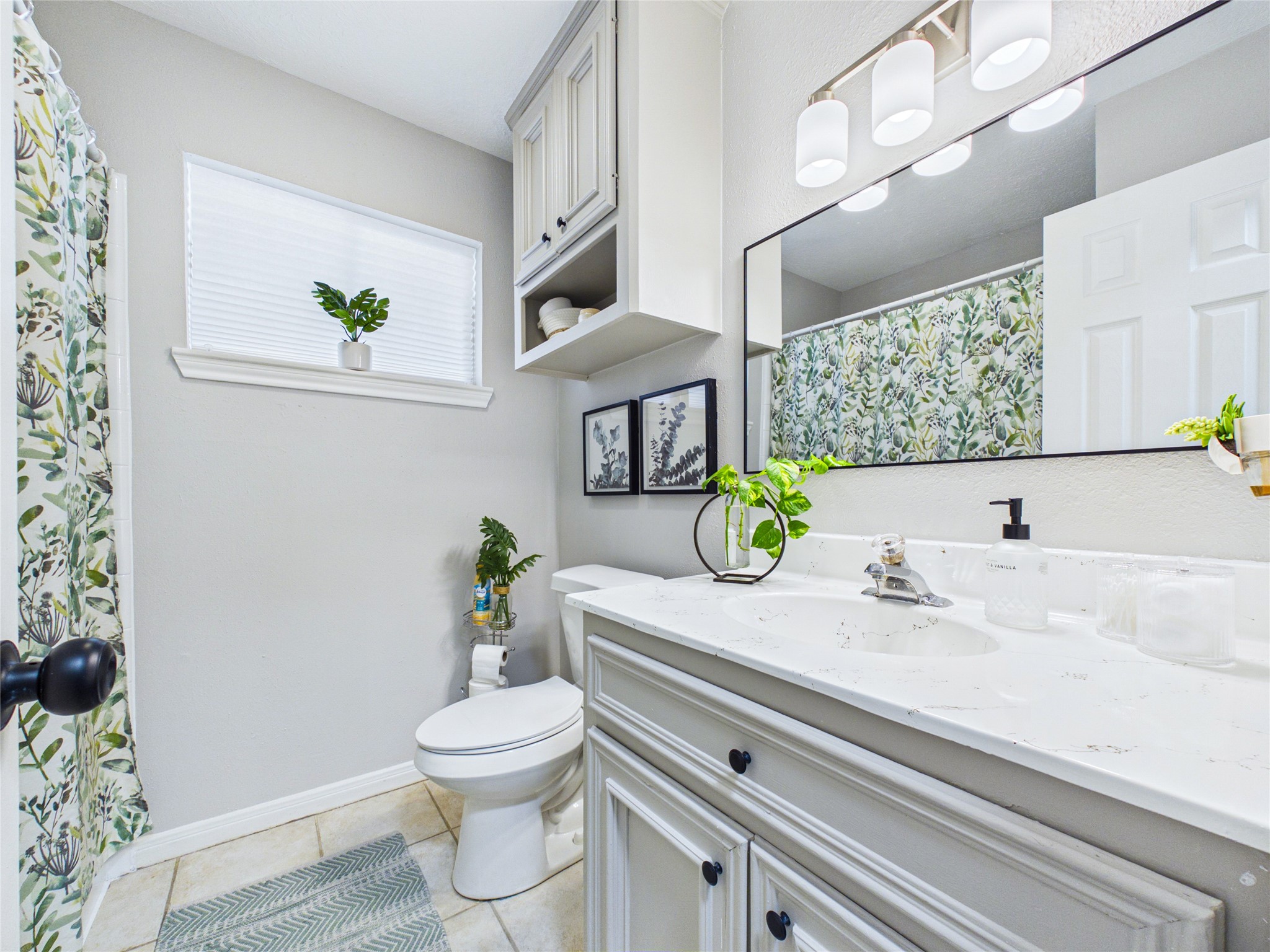 Bright and inviting guest bathroom featuring a sleek vanity with ample storage, a large mirror, and stylish lighting.