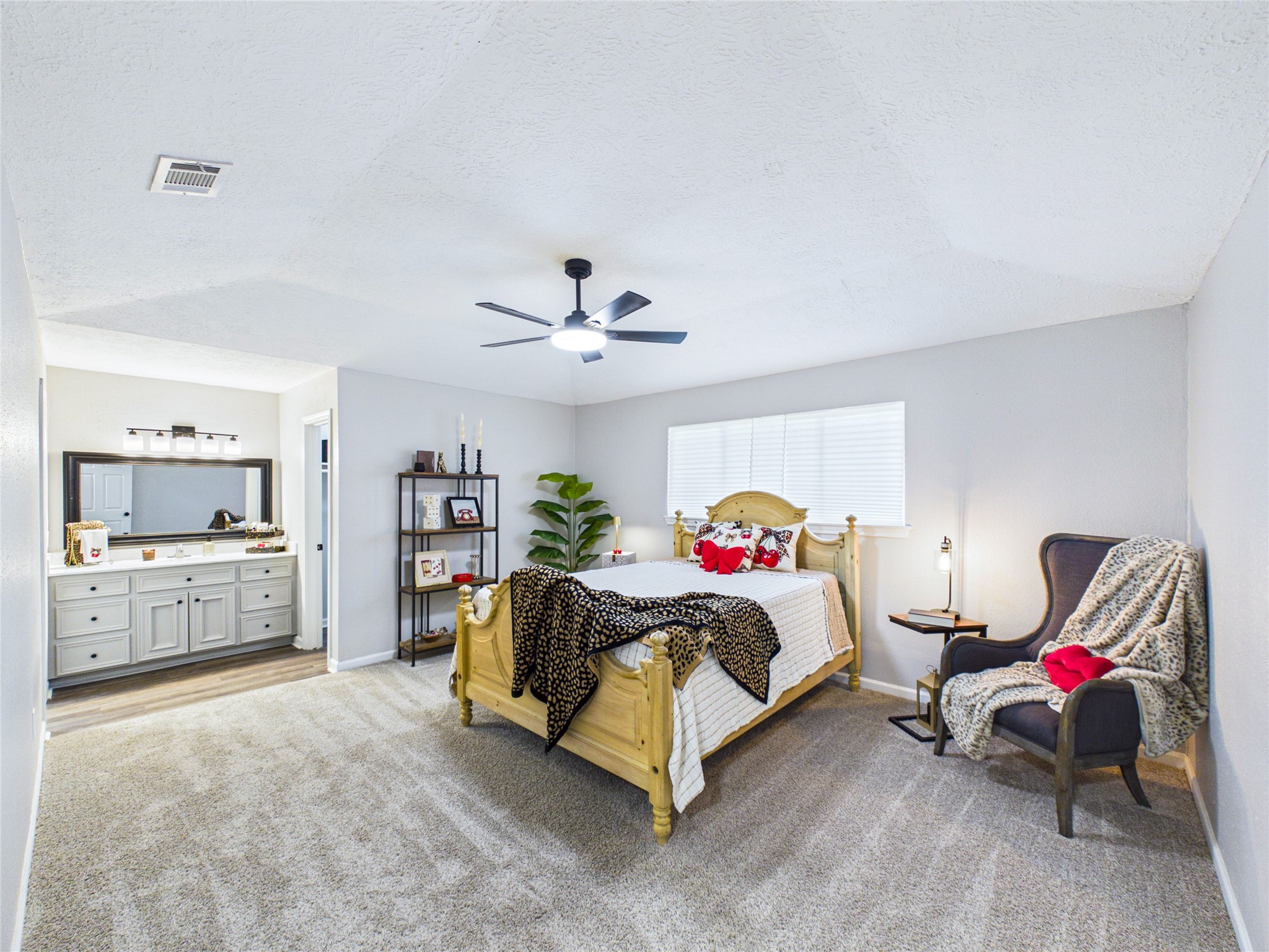 Spacious Primary bedroom featuring new carpeting, and an en-suite bathroom with a vanity.
