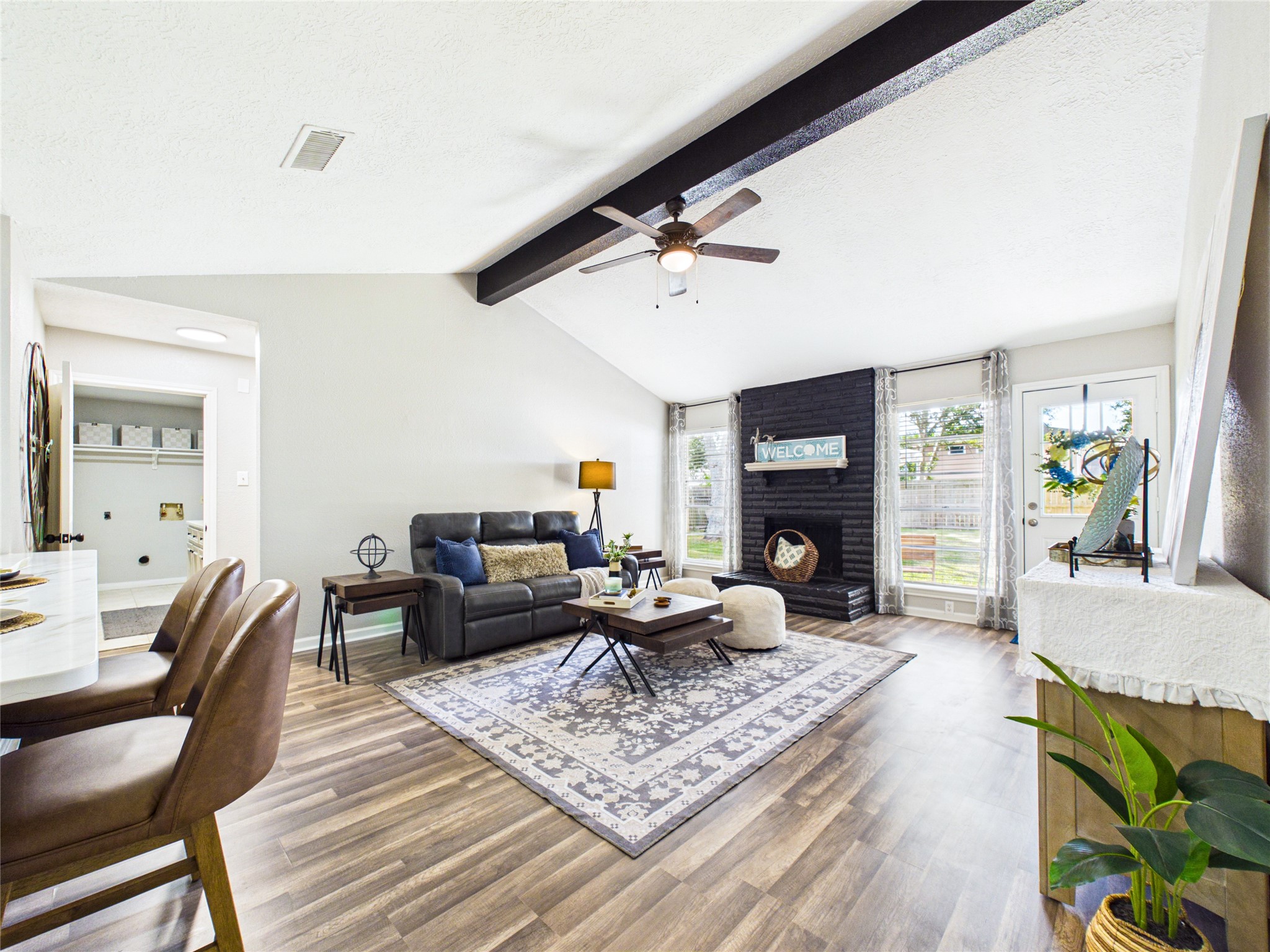 Bright and inviting living space with vaulted ceilings, featuring a cozy seating area, a stylish black accent wall, and large windows that fill the room with natural light. Bright and inviting living space with vaulted ceilings, featuring a cozy seating area, a stylish black accent wall, and large windows that fill the room with natural light.