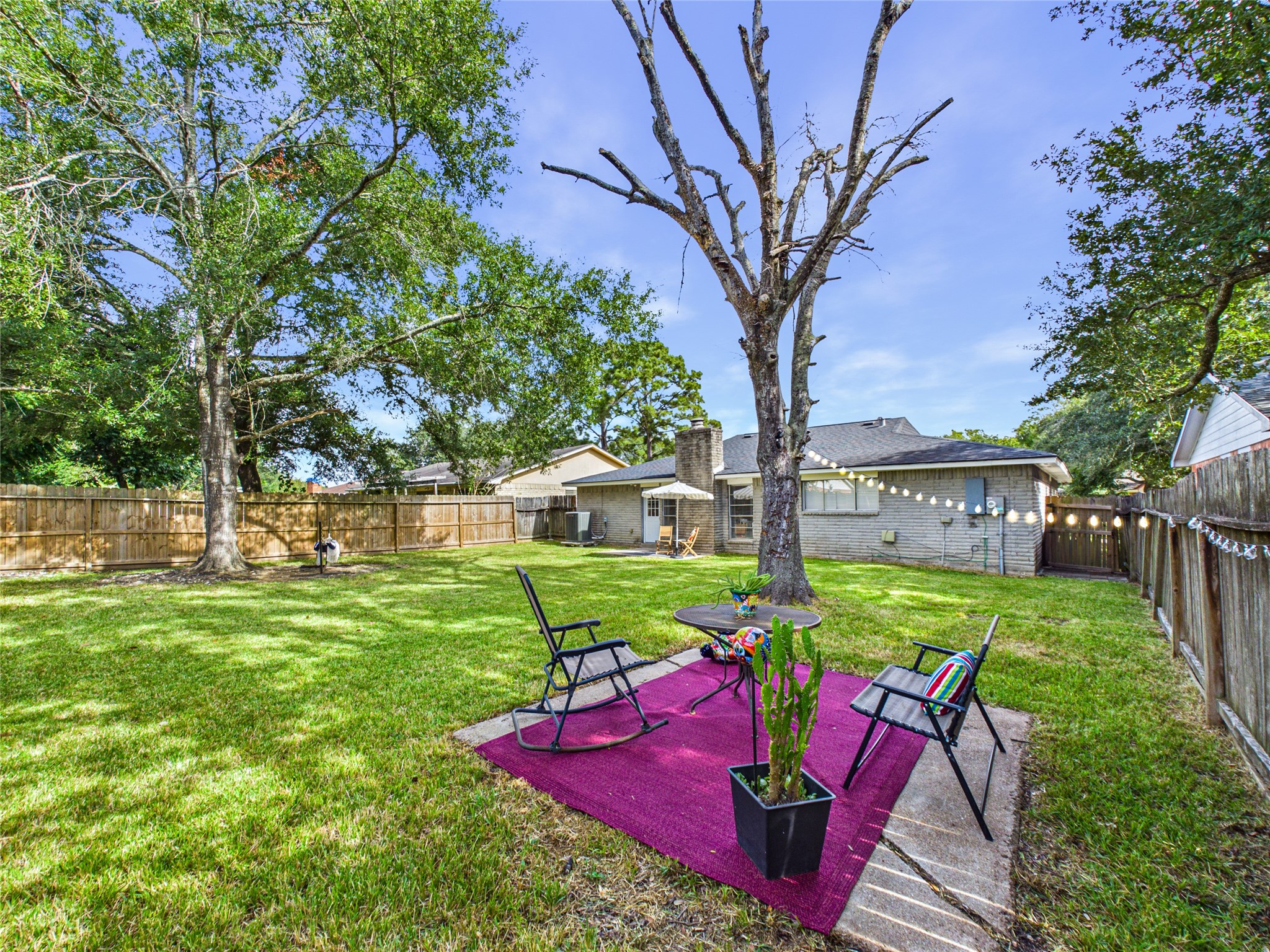 The spacious backyard with lush green lawn, mature trees, and a cozy seating area perfect for outdoor relaxation and entertaining.