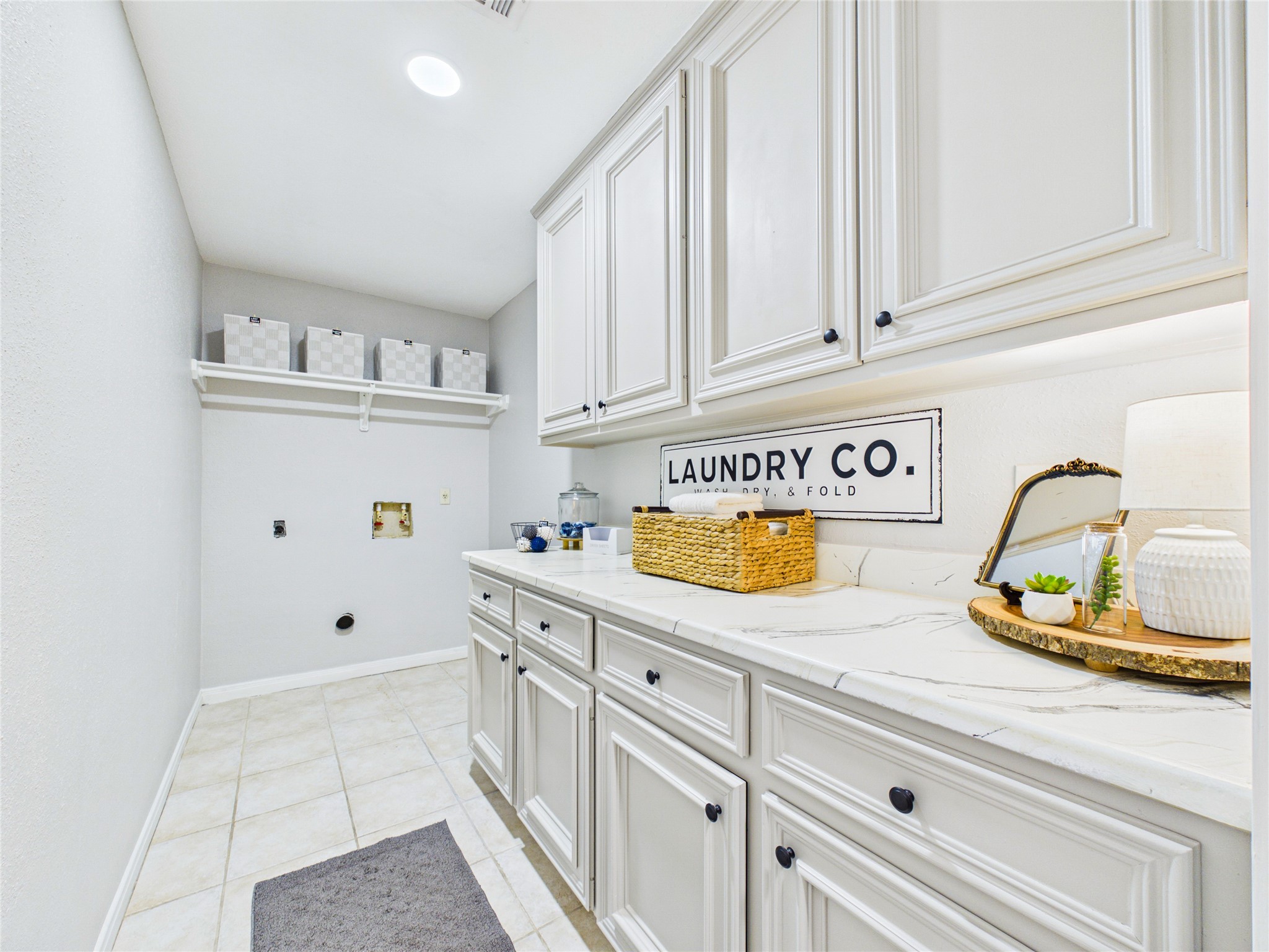 Bright and spacious laundry room featuring ample cabinetry, sleek countertops, and organized shelving for a functional and stylish workspace.