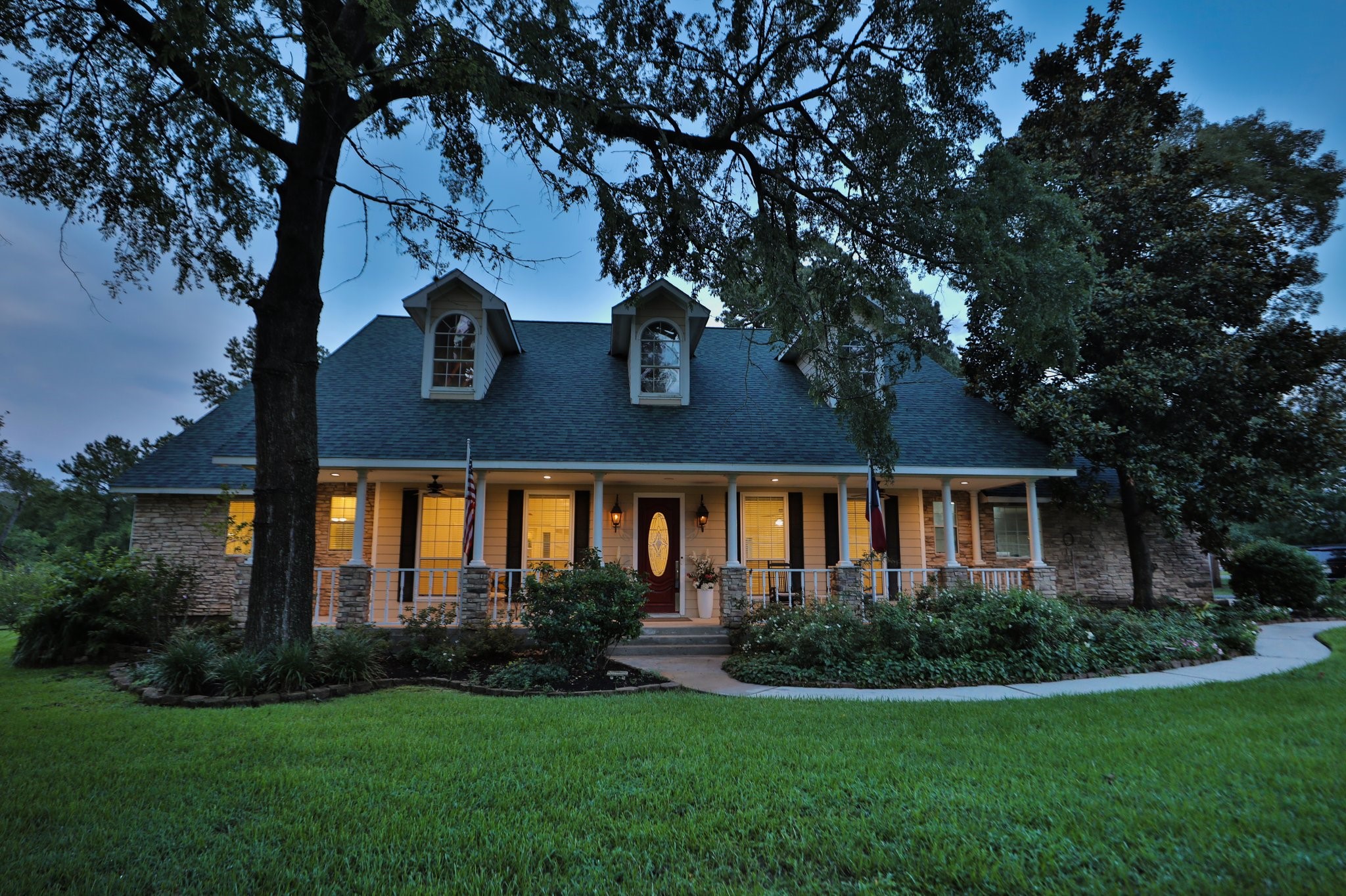 Charming, two-story home with a welcoming front porch and dormer windows. Surrounded by lush greenery and mature trees, it features a well-maintained lawn and a pathway leading to the entrance. Perfect for a cozy, inviting atmosphere. Charming, two-story home with a welcoming front porch and dormer windows. Surrounded by lush greenery and mature trees, it features a well-maintained lawn and a pathway leading to the entrance. Perfect for a cozy, inviting atmosphere.
