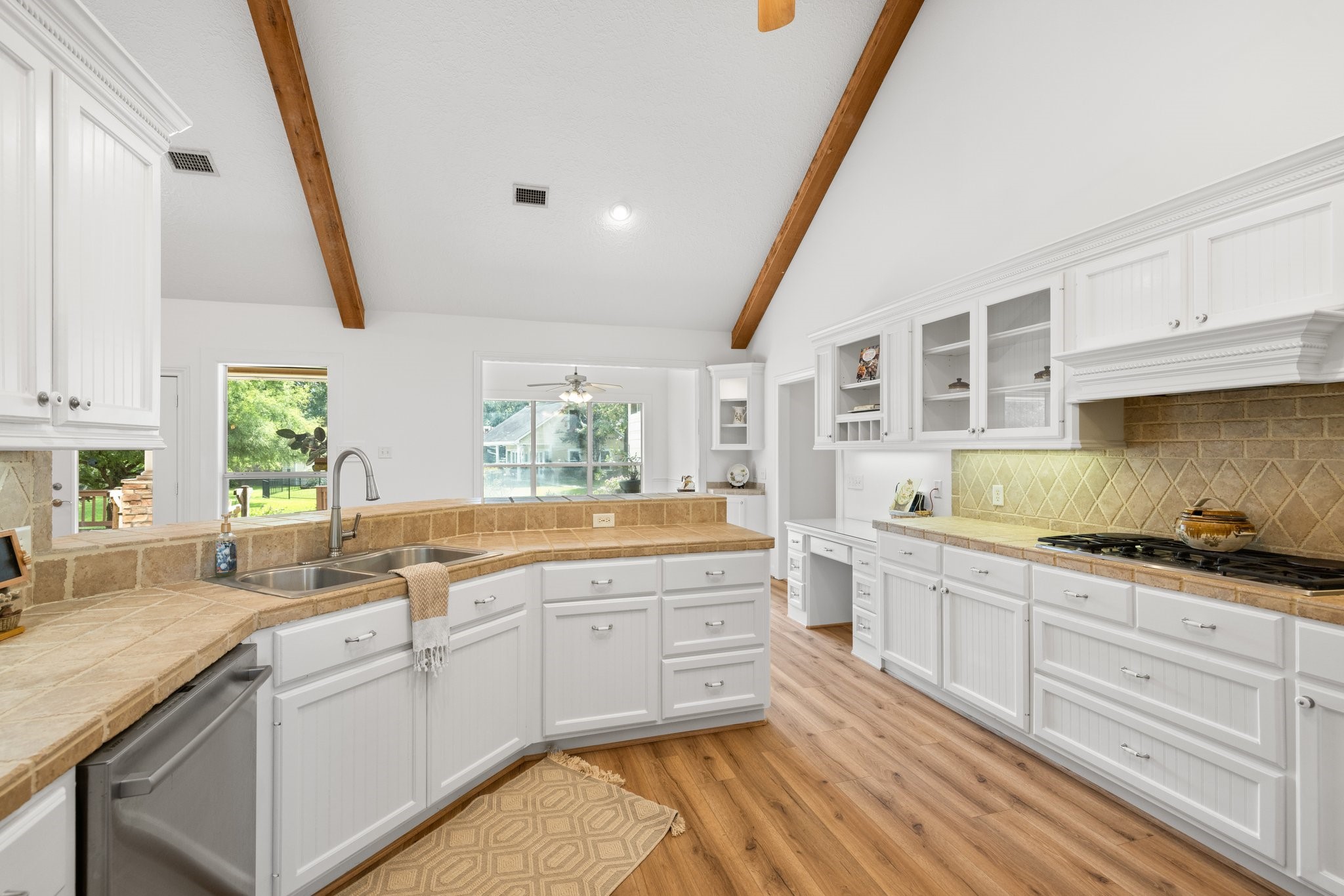 This kitchen features abundant cabinets for storage, expansive counters for meal prep, and a convenient desk for organizing recipes or handling bills.