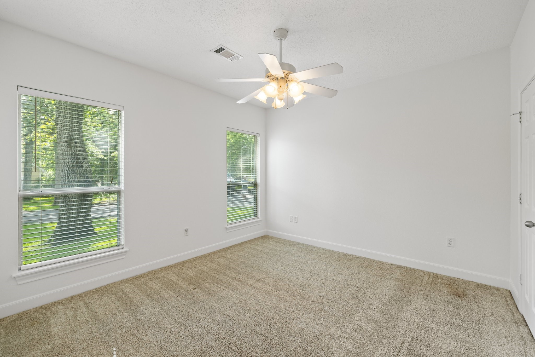 Bright secondary bedroom with ensuite bath, featuring new carpet and a ceiling fan.