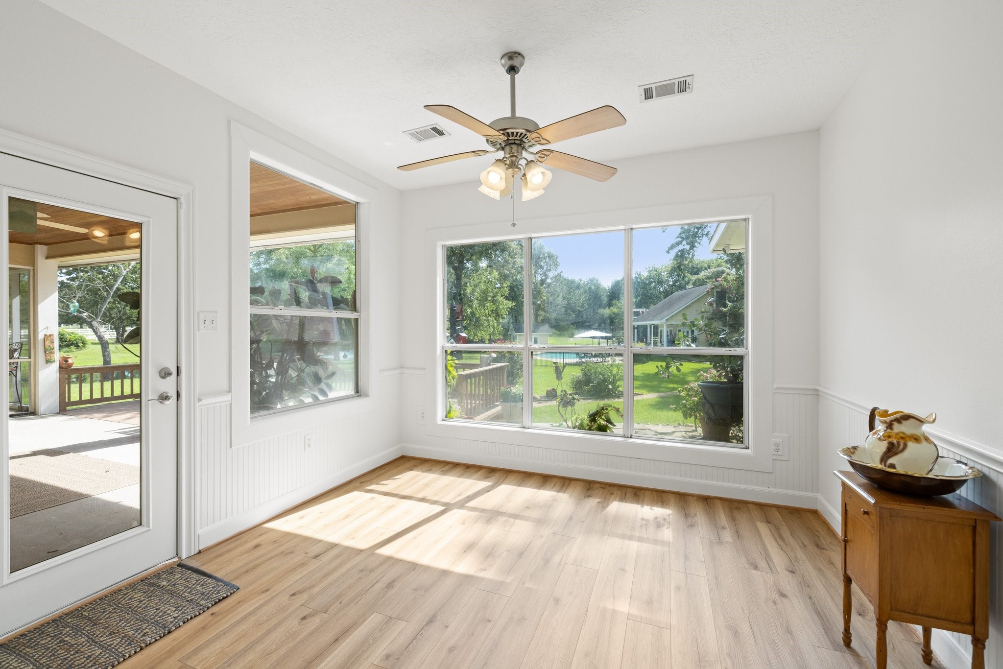 Bright and airy breakfast area with large windows, offering beautiful views of the backyard. Features beautiful vinyl plank flooring, a ceiling fan, and access to a covered patio. Perfect for relaxing or entertaining.
