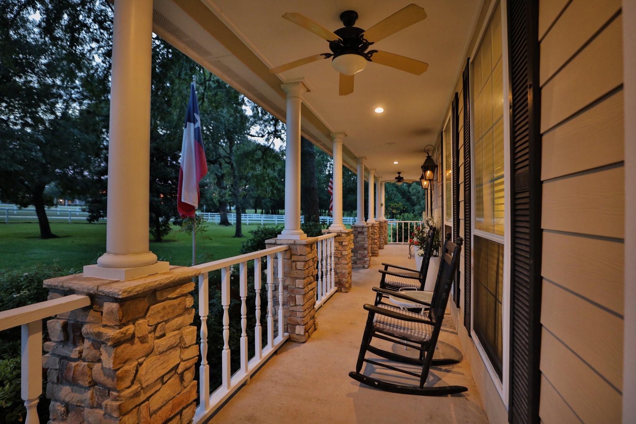 This inviting home features a spacious front porch with stone pillars, ceiling fans, perfect for relaxing. Surrounded by lush greenery it offers a serene setting for outdoor enjoyment. This inviting home features a spacious front porch with stone pillars, ceiling fans, perfect for relaxing. Surrounded by lush greenery it offers a serene setting for outdoor enjoyment.