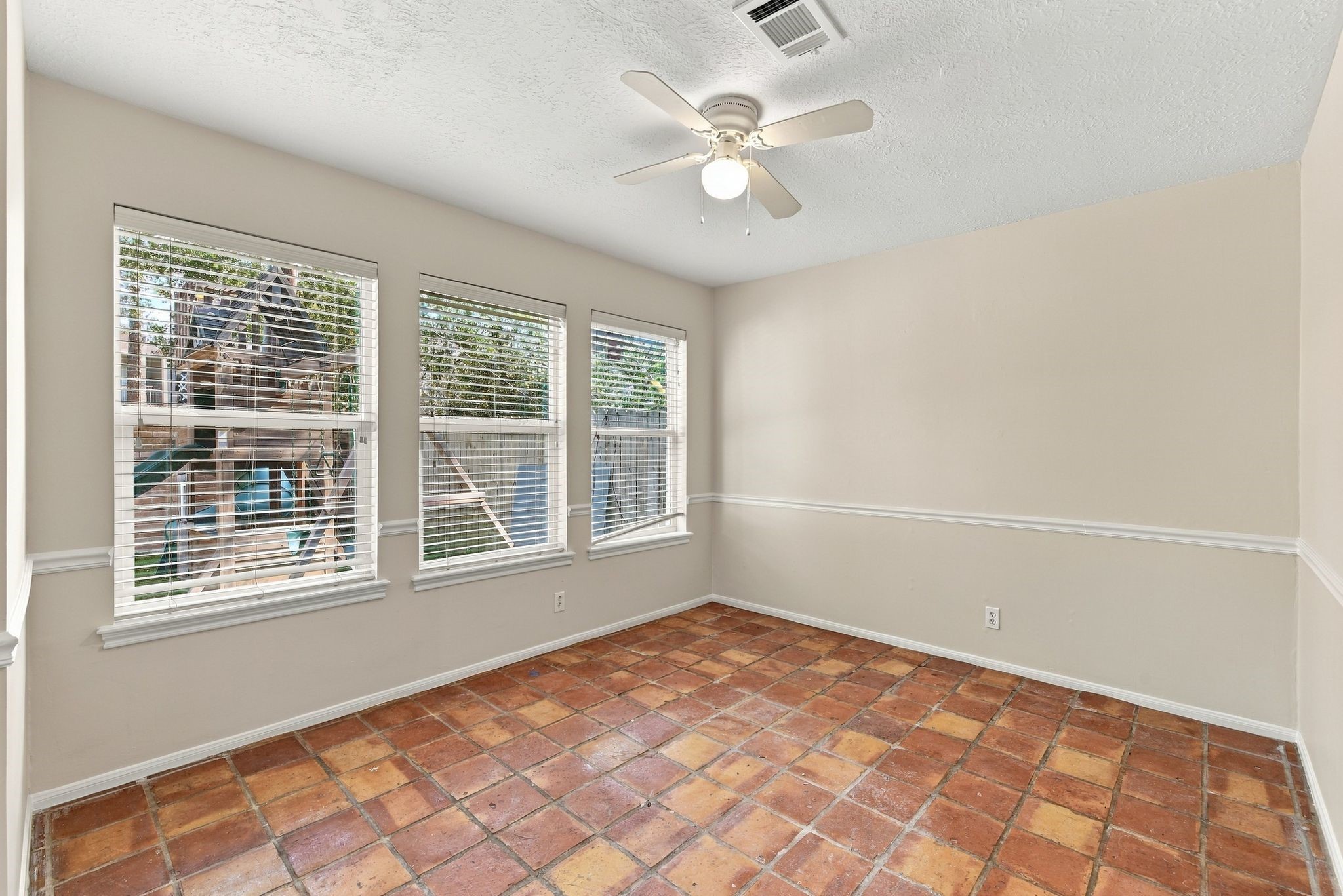 Bright breakfast nook showcasing multiple windows and distinctive Saltillo tile flooring.