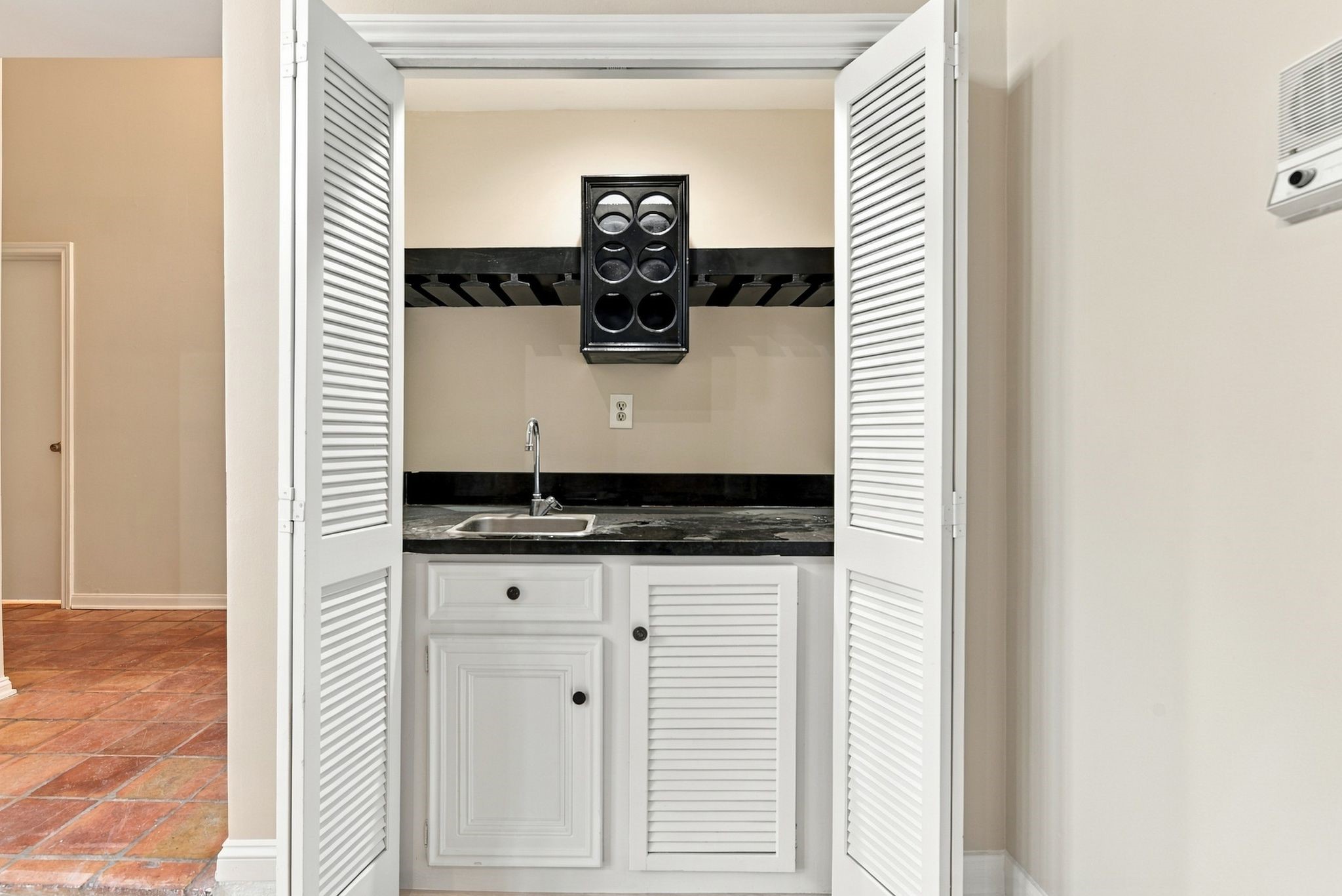 Convenient built-in wet bar with sink, cabinetry, wine bottle/glass storage and countertop space, located just off the main living area.