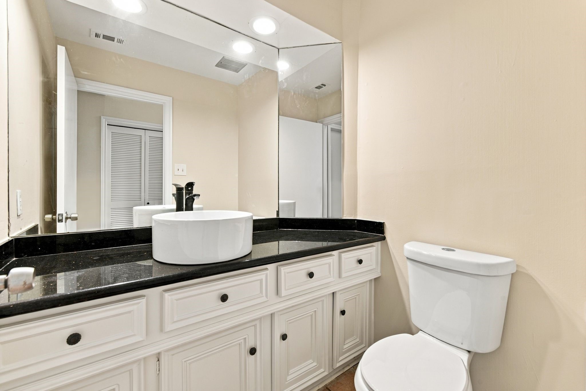 Conveniently located half bath near the entryway, featuring a spacious vanity with granite countertop and ample cabinet storage.