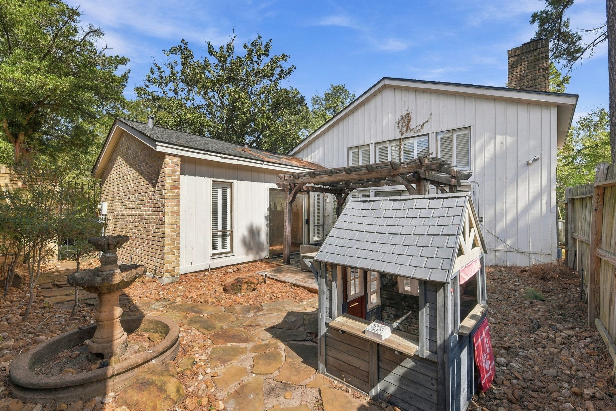 Private outdoor retreat accessible from the primary bedroom, featuring a wooden pergola and intimate courtyard setting.