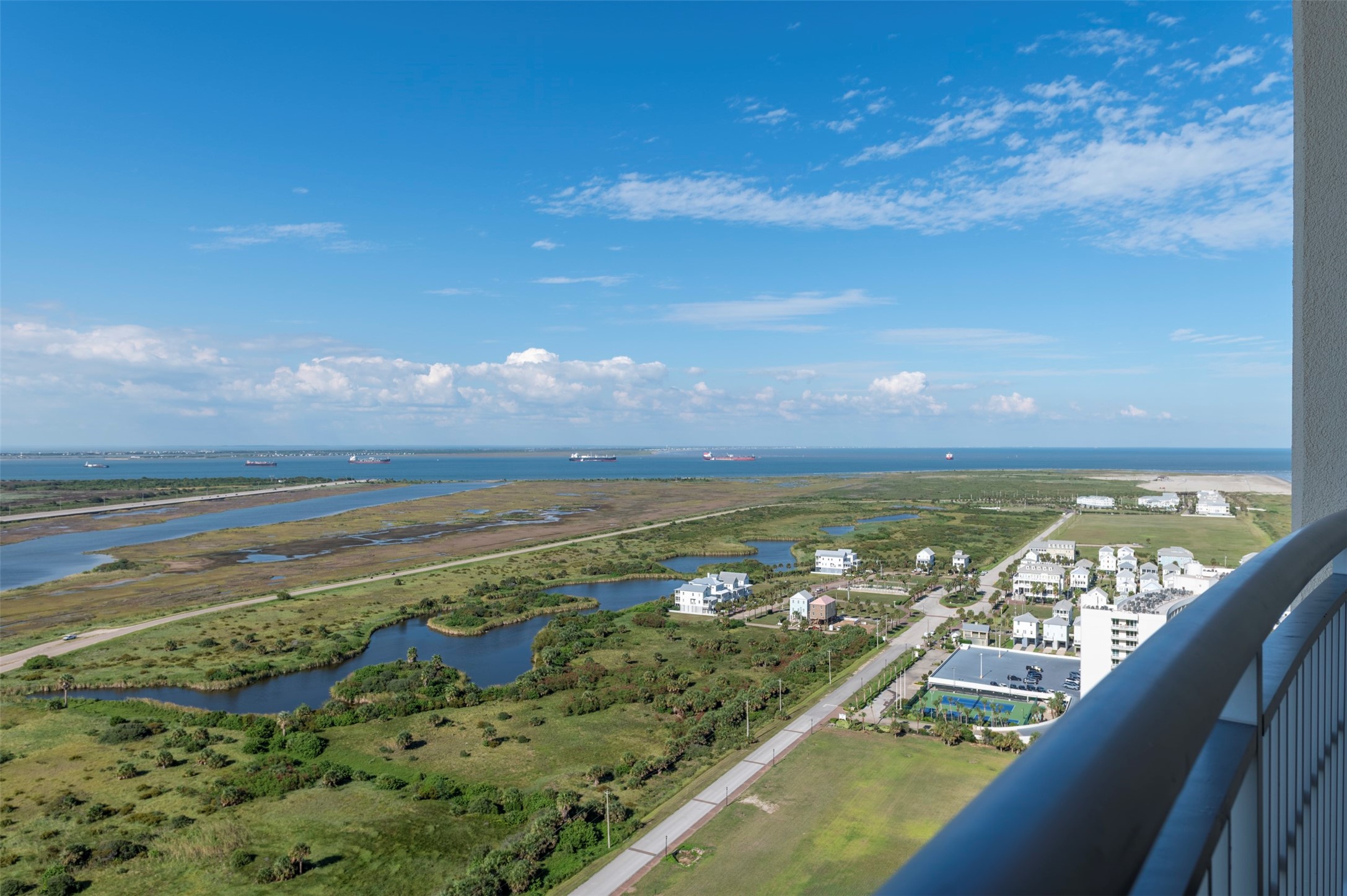 Expansive eastward views from your master balcony stretch across the wetlands and bay, with ships in the channel and the island extending into the distance.
