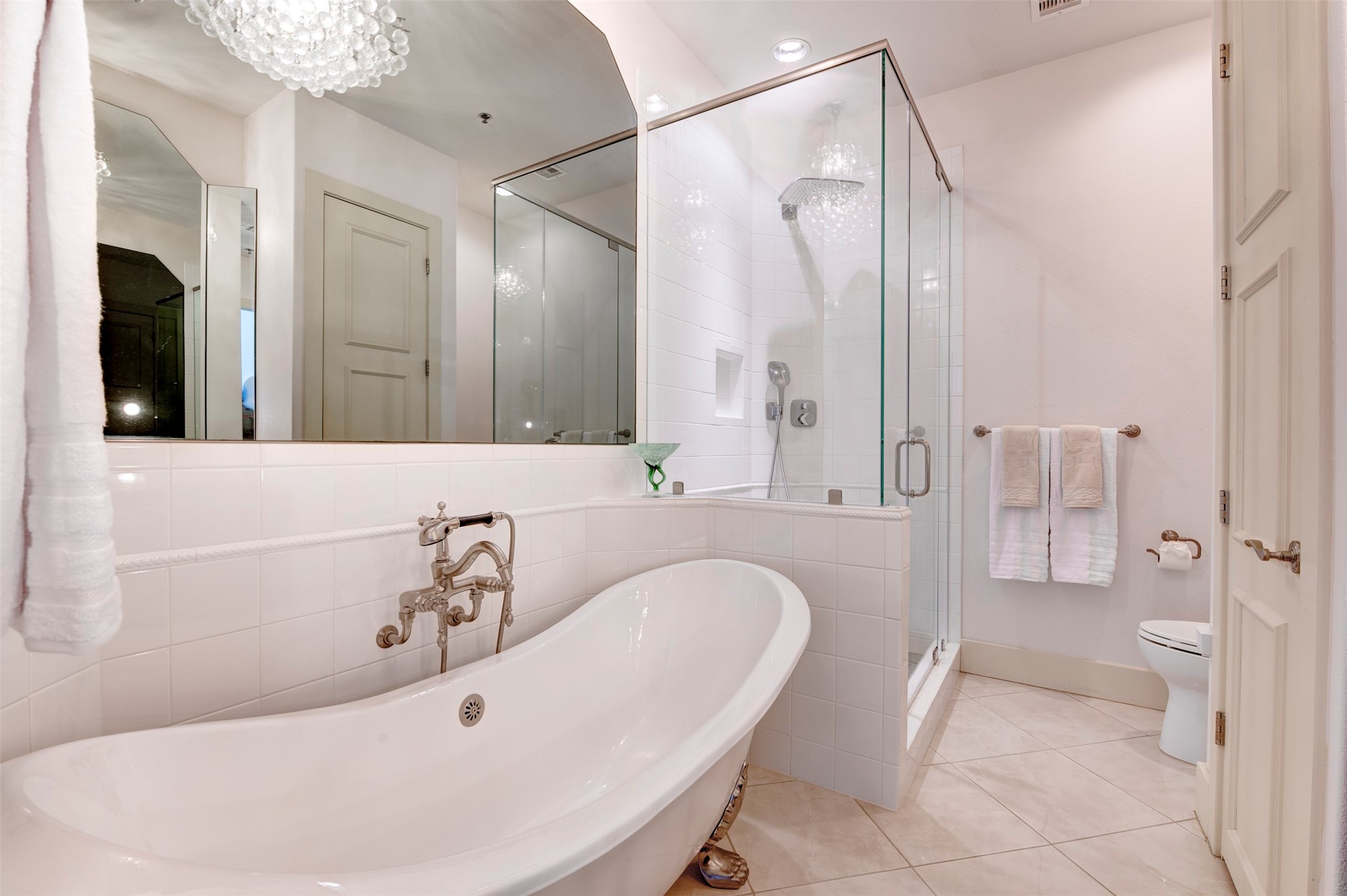 Claw-foot tub and oversized glass shower are complemented by crystal lighting