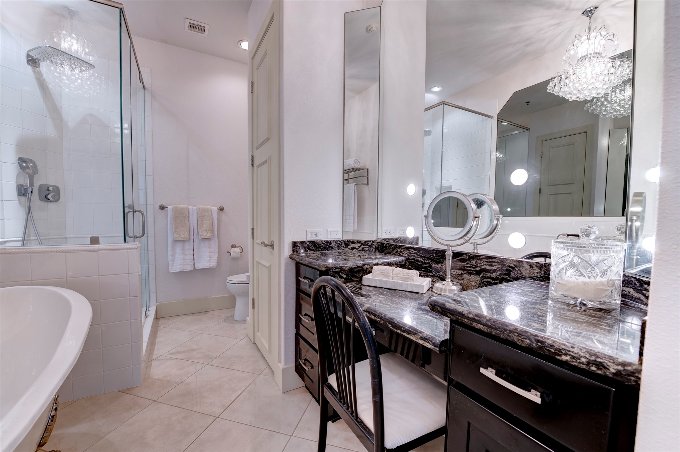Primary bath features a generous seated vanity area, extensive mirror space and a large glass-enclosed shower.