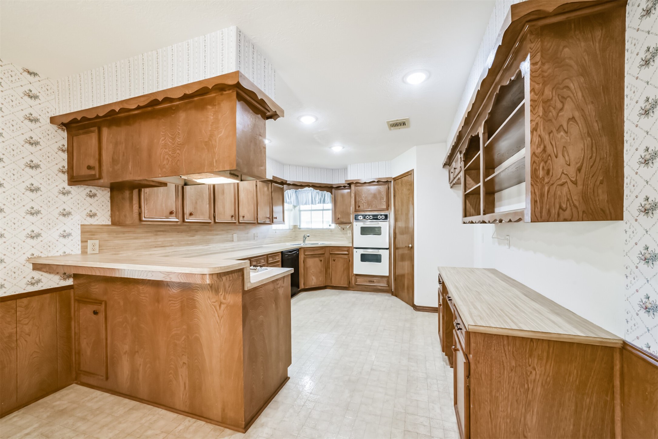 Heres another view of the kitchen from the dining area, highlighting the thoughtful storage and charming built-in features. A spacious pantry offers plenty of room for essentials, while the built-in buffet provides the perfect place to display cherished collectibles, family heirlooms, or decorative accents.