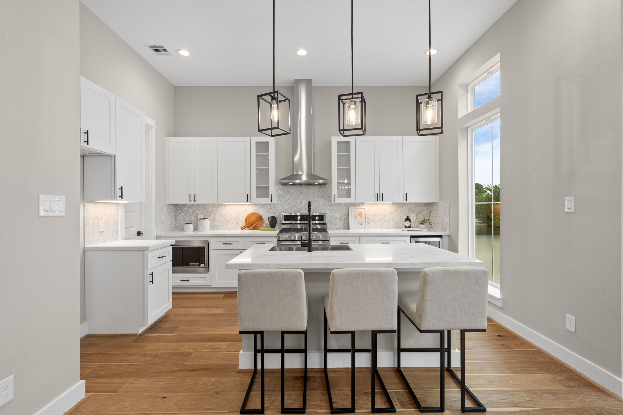 Stunning kitchen with walk-in pantry and beautiful island with overhead fixtures.