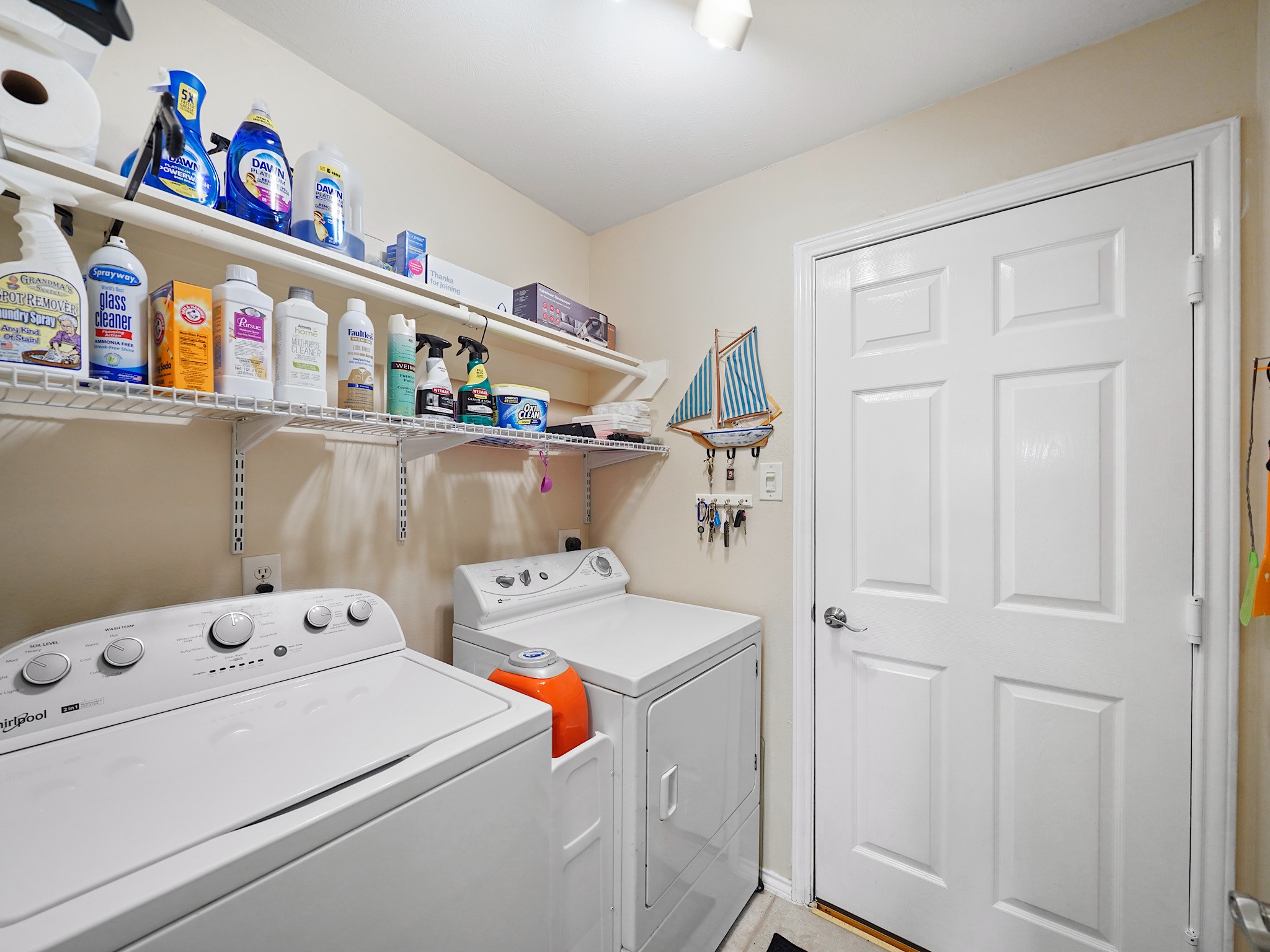 The utility room offers space for a side-by-side washer and dryer, with overhead shelving to keep laundry essentials within reach.