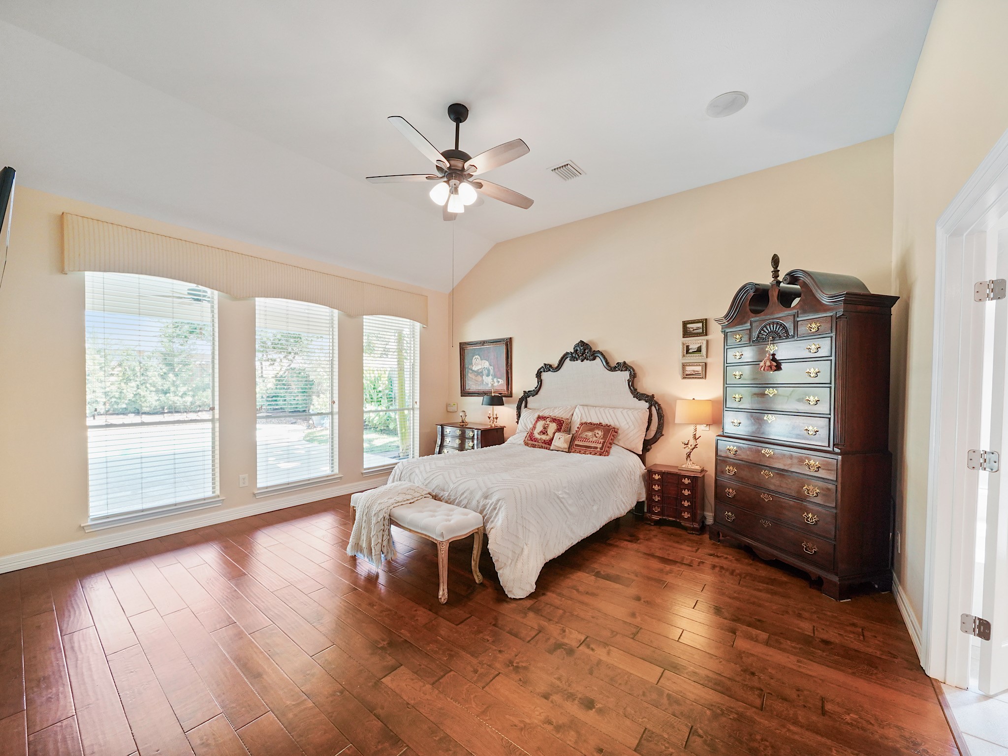 The downstairs primary retreat offers a peaceful place to unwind, with wood flooring and generous windows that welcome in natural light. Its spacious layout creates a comfortable setting to begin and end each day.