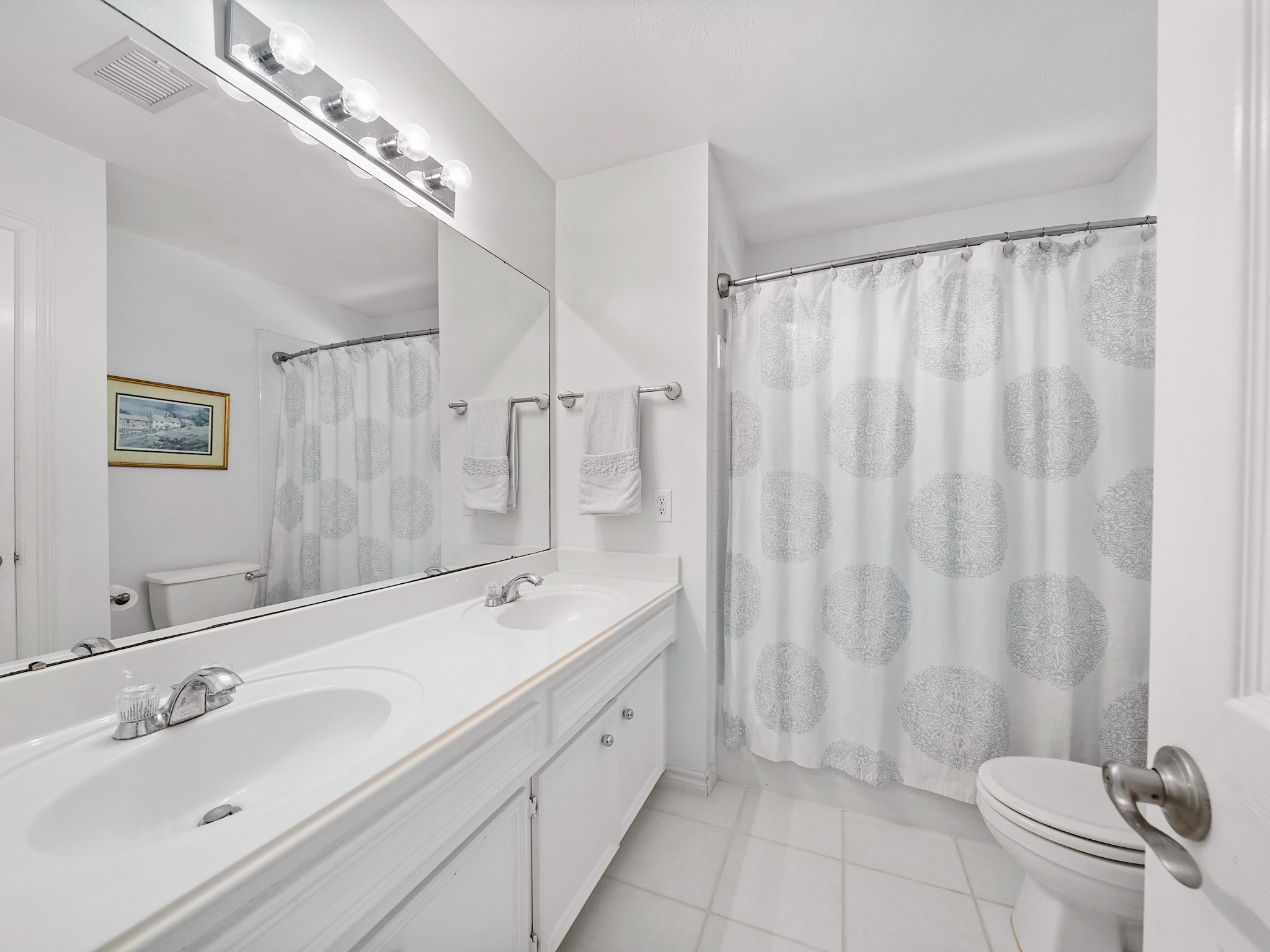 The upstairs bathroom features a dual-sink vanity with storage and a tub-and-shower combination. Its practical layout makes busy mornings and evening routines a little easier.