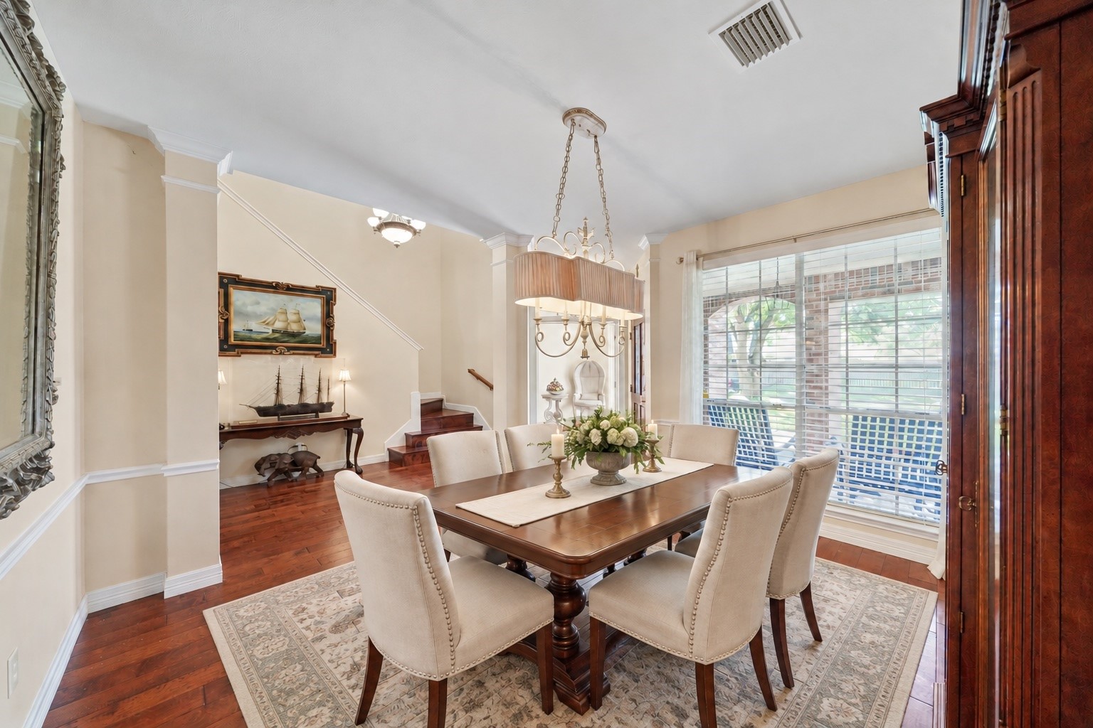 Virtually Staged: This formal dining room has been styled to show how comfortably the space can host family dinners and special occasions. Warm wood flooring and a large window create an inviting backdrop for gatherings.