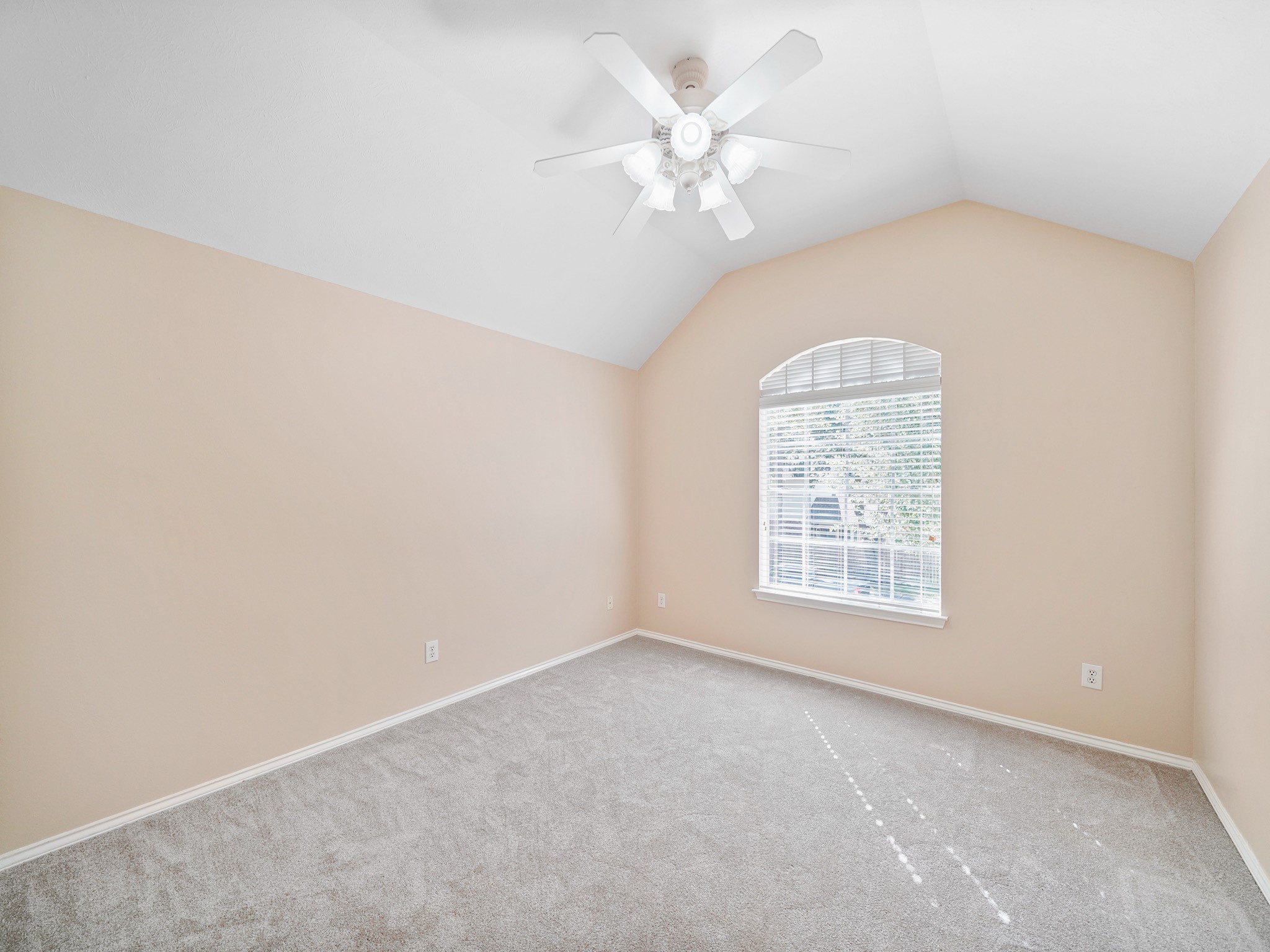 An arched window and vaulted ceiling add character to this secondary bedroom. The bright, open feel makes it an inviting space to furnish as a bedroom, guest room, or hobby room.