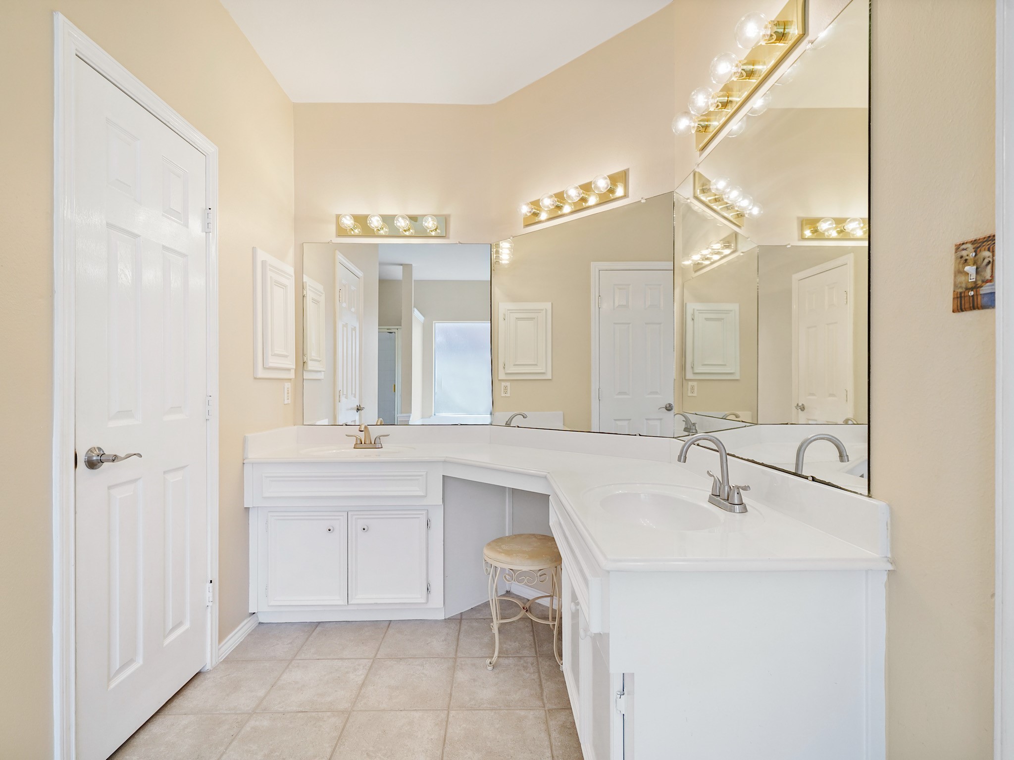 An extended dual-sink vanity provides plenty of room for daily routines, with cabinet storage and a seated vanity area. Everything has its place in this bright and spacious bath.