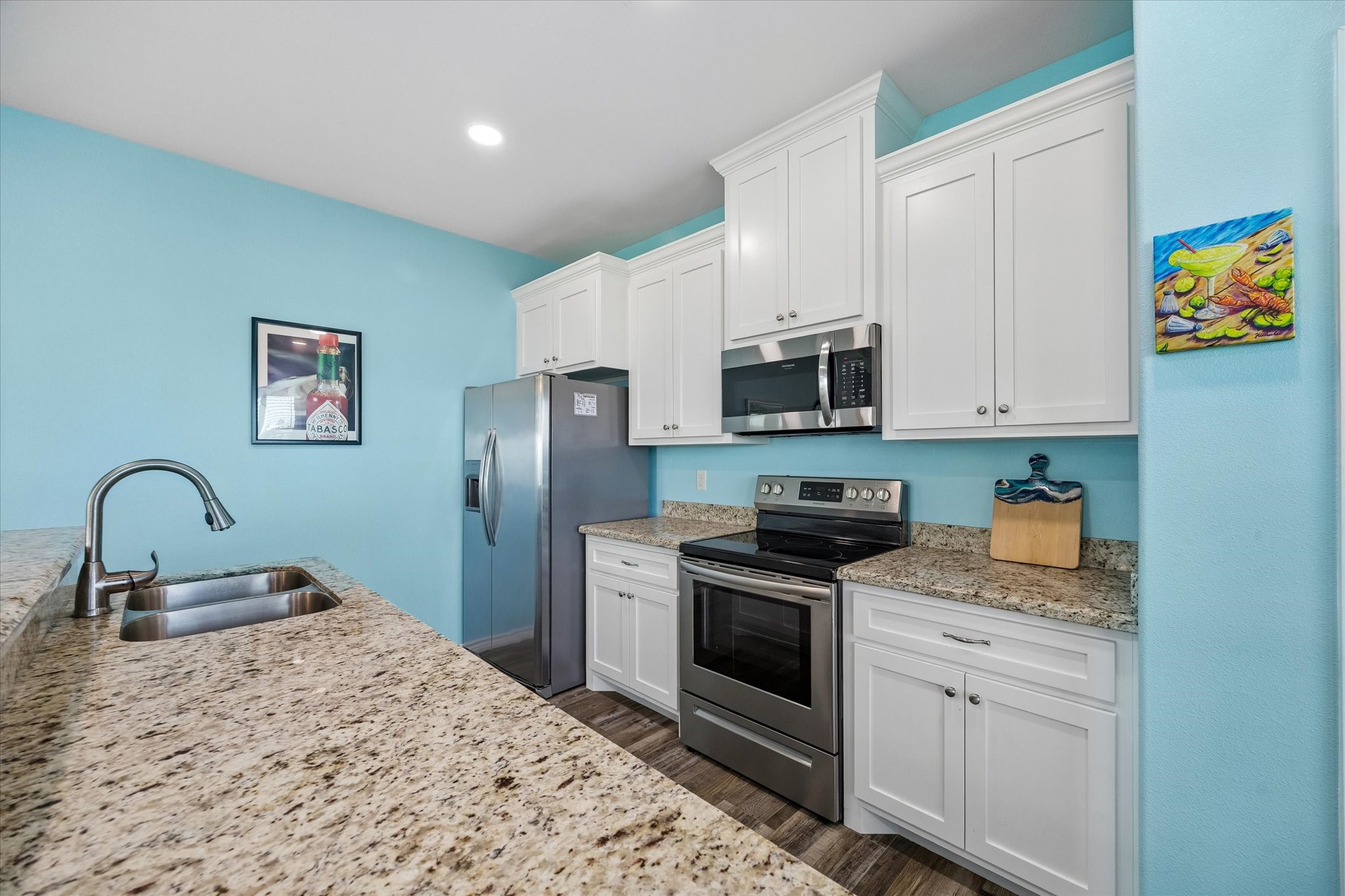 A bright and inviting kitchen features granite countertops, stainless steel appliances, and crisp white cabinetry set against a cheerful blue backdrop. A bright and inviting kitchen features granite countertops, stainless steel appliances, and crisp white cabinetry set against a cheerful blue backdrop.