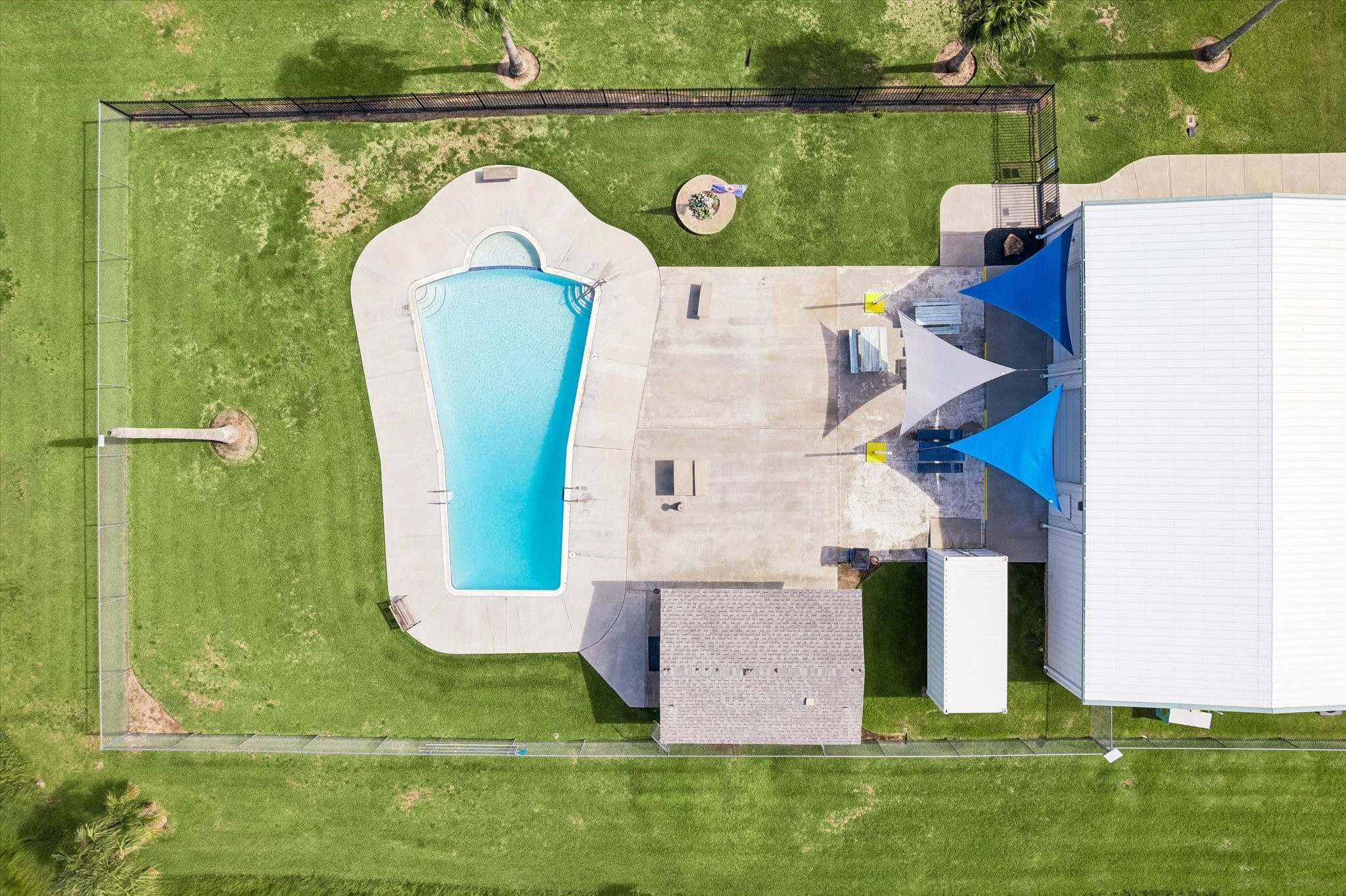 Spacious Nieborhood oasis featuring a sparkling pool, expansive patio with shade sails, and lush green lawn, perfect for outdoor entertaining and relaxation.
