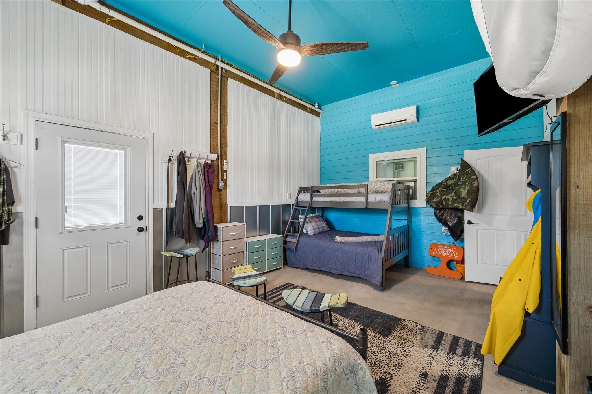 Bright and spacious bedroom featuring high ceilings, a ceiling fan, and colorful accents, and a convenient exterior door.
