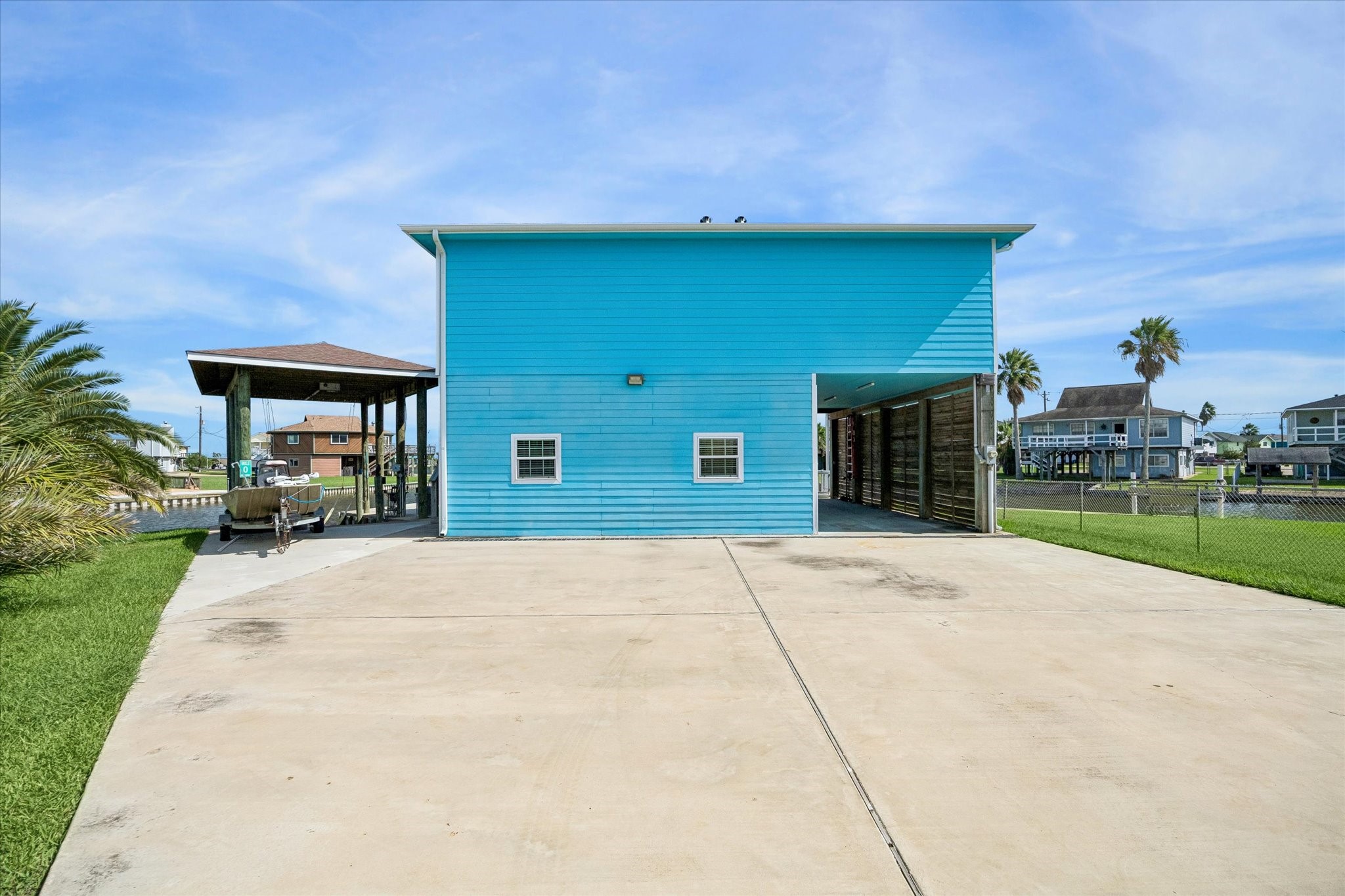 A vibrant blue waterfront home with a spacious driveway, inviting covered patio, and direct canal accessperfect for boating enthusiasts.