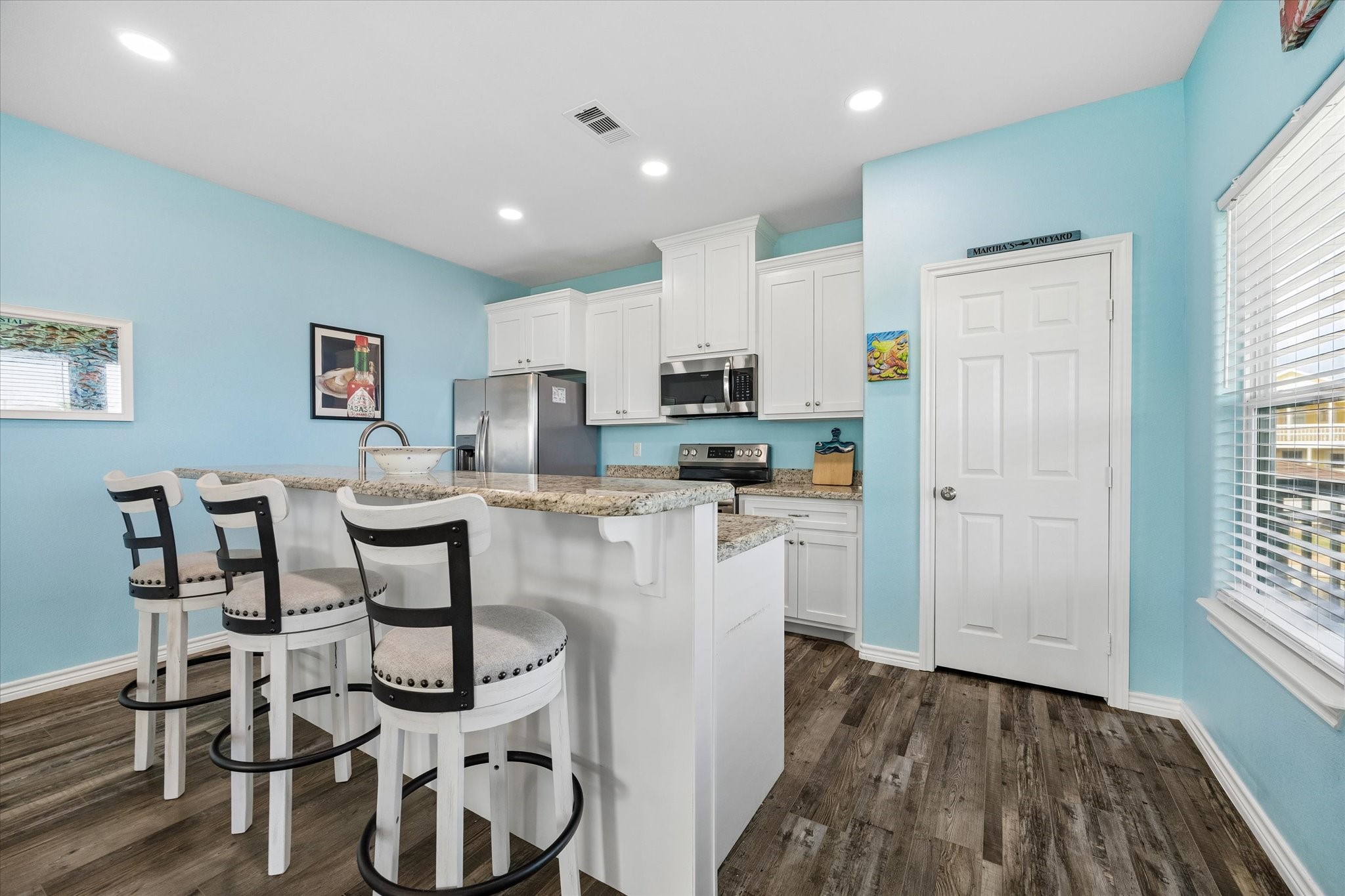 A bright and inviting kitchen with sleek white cabinetry, granite countertops, and a cozy breakfast bar featuring stylish seating. A bright and inviting kitchen with sleek white cabinetry, granite countertops, and a cozy breakfast bar featuring stylish seating.