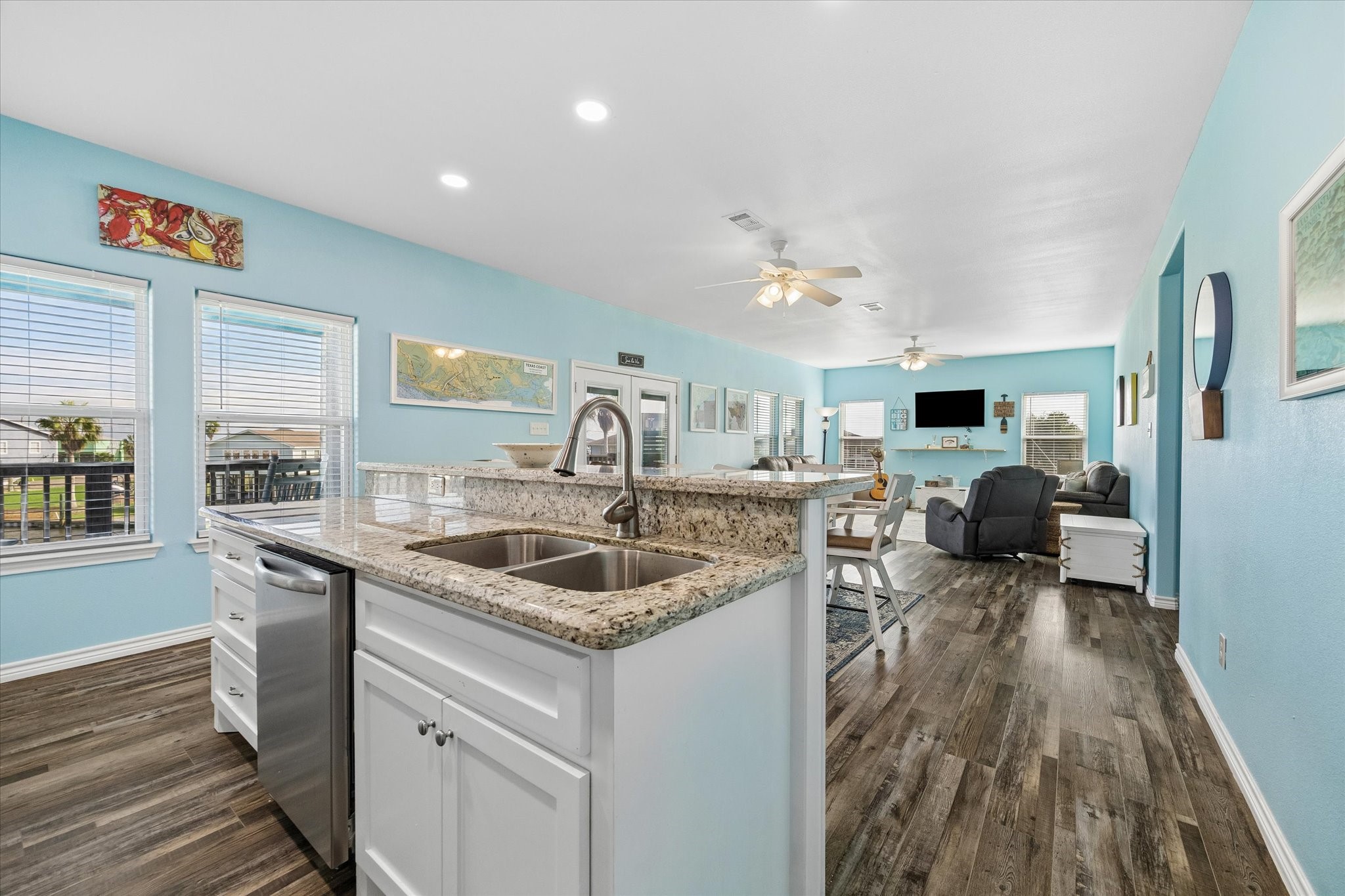 Bright and spacious open-concept living area with stylish wood flooring, modern kitchen featuring granite countertops, and ample natural light from large windows.