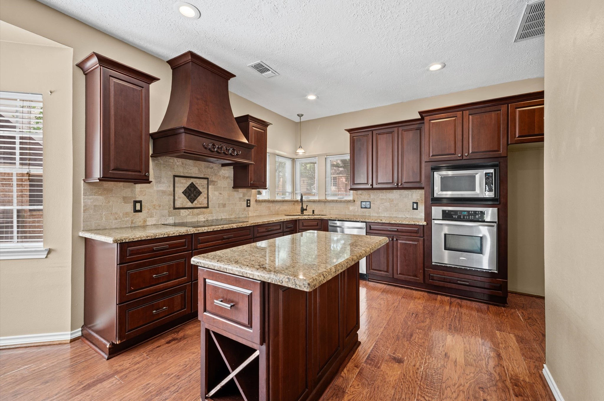 This gorgeous kitchen is open to living room and features beautiful soft close cabinetry with granite countertops, functional island, wood floors, large breakfast area and a chef's planning station.