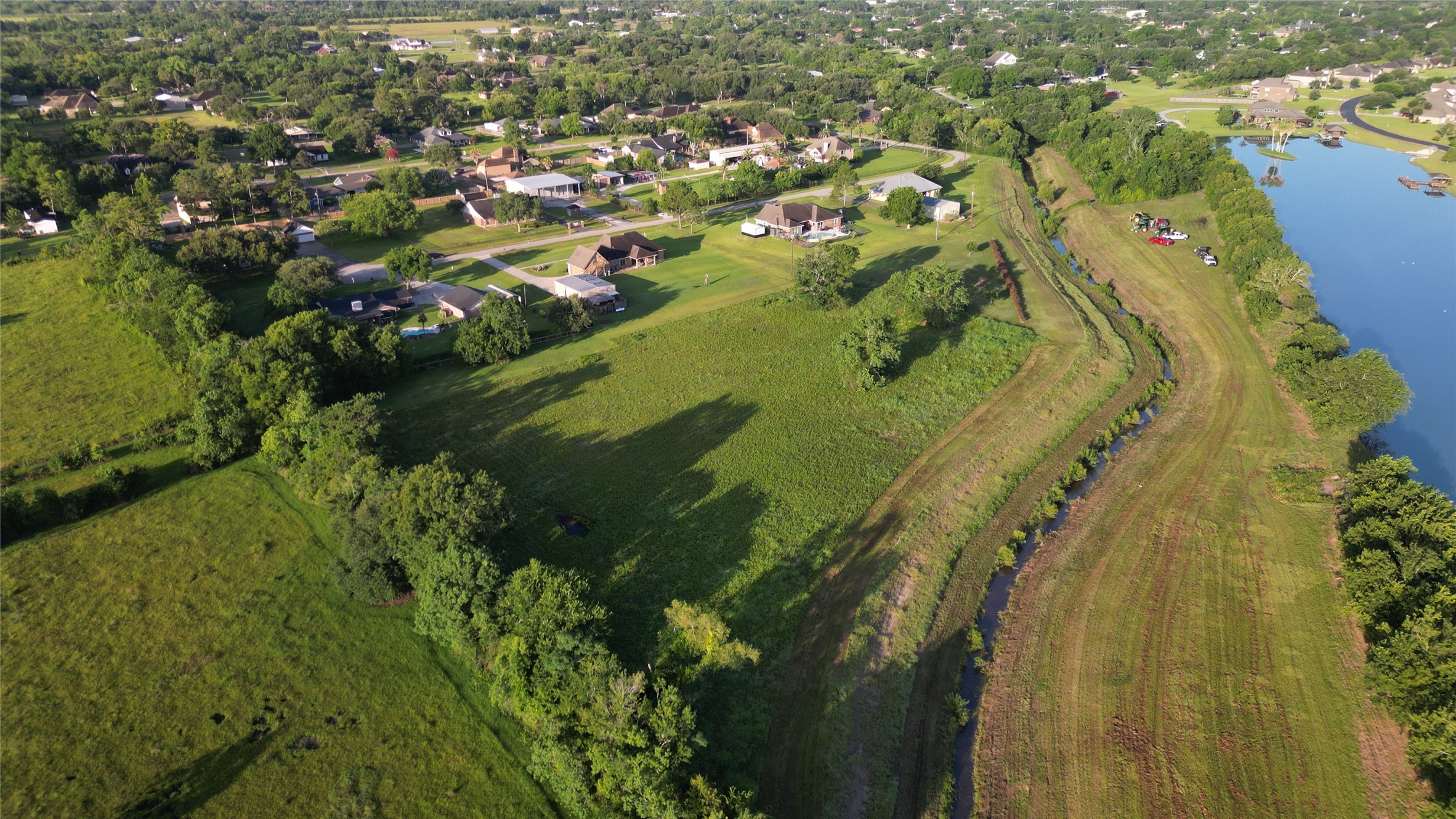Another view of the ideal location tucked between custom homes, trees and a lake just on the other side of a drainage channel.