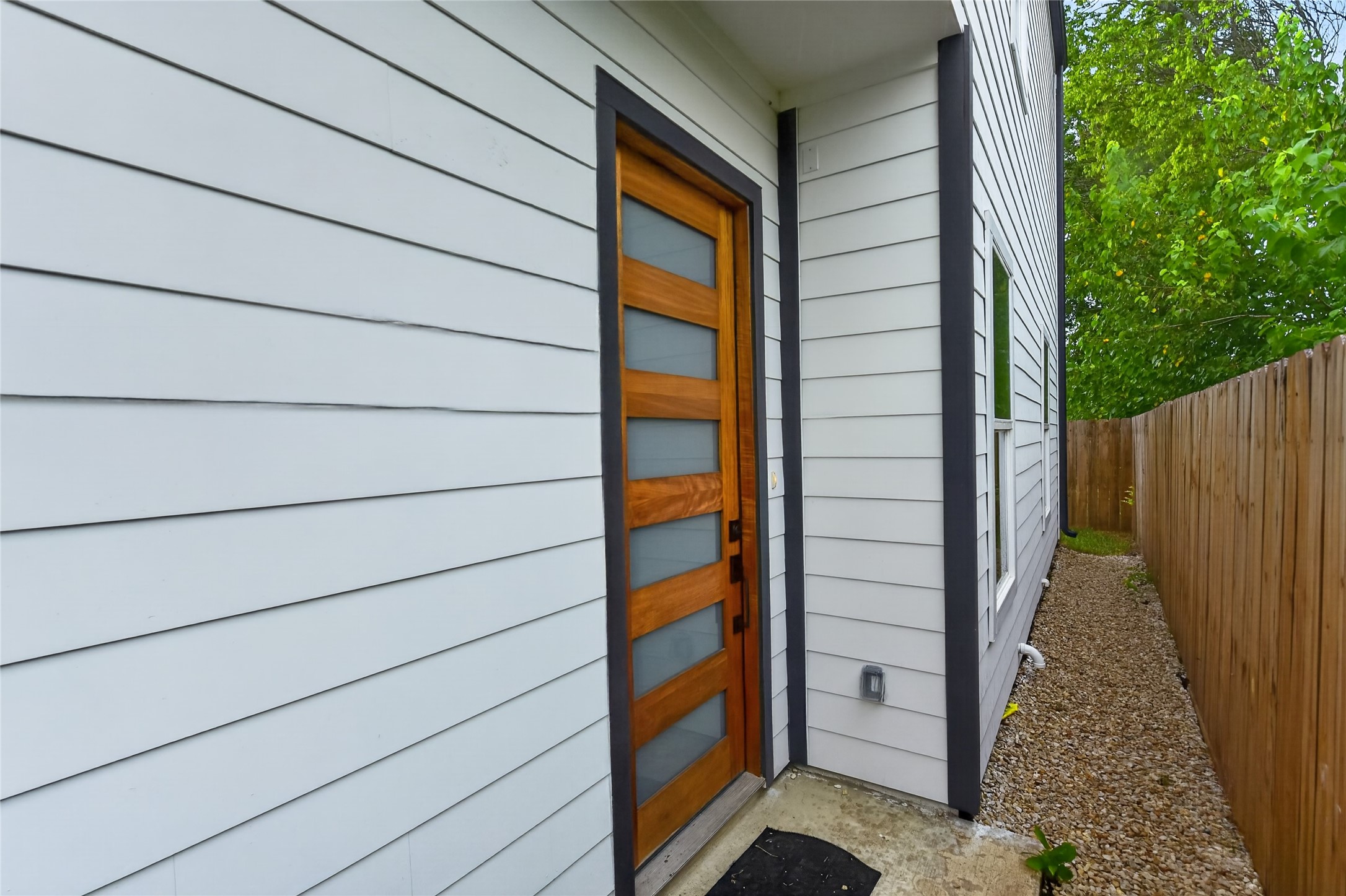 A concrete walkway leads to the contemporary front door, opening into bright, connected living spaces that flow naturally through to the backyard.