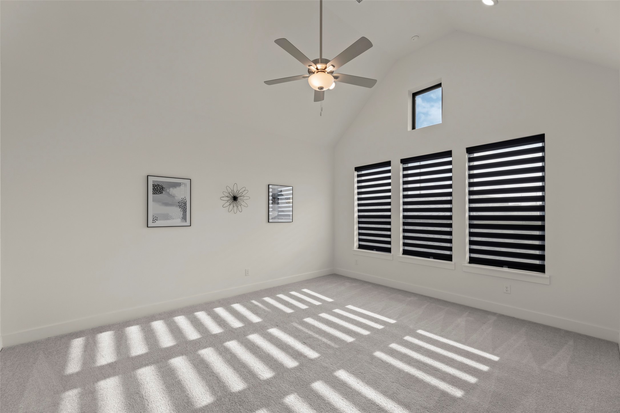 Beautiful room with vaulted ceilings, modern ceiling fan, and stylish striped window blinds, perfect for a cozy retreat.