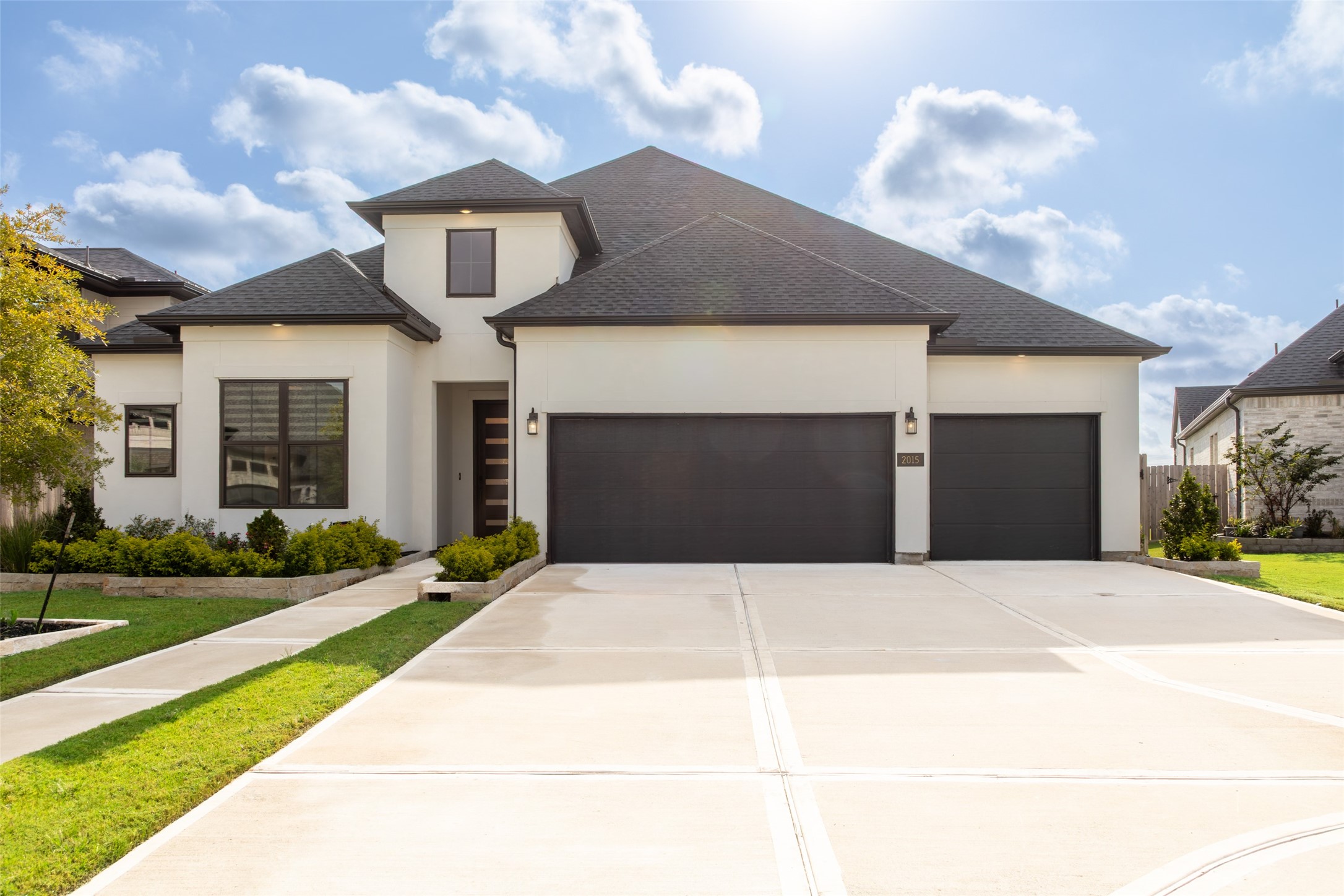 Modern home with black and white exterior, featuring a spacious three-car garage.