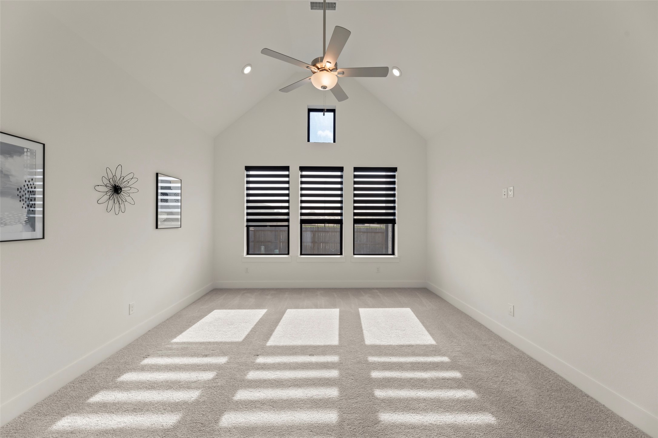 Primary bedroom with high ceilings, abundant natural light, and modern fan, perfect for relaxation or entertainment.