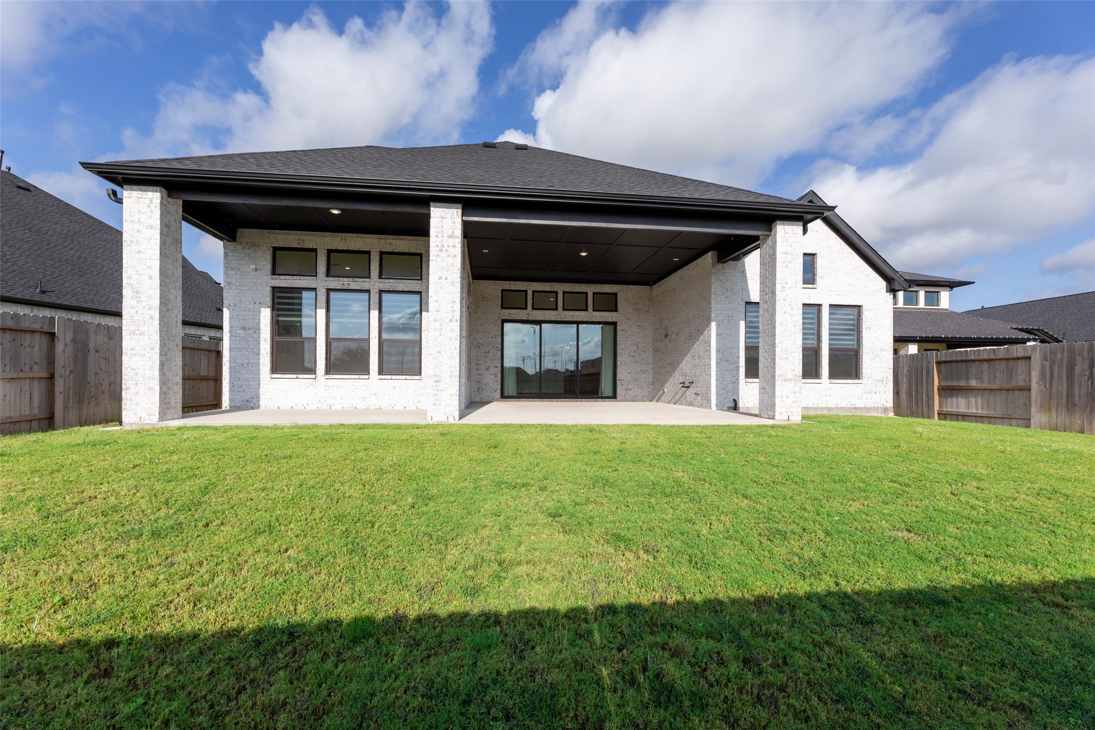 Maintained backyard with a covered patio, perfect for outdoor entertainment and relaxation, complemented by a modern exterior and large windows for natural light.