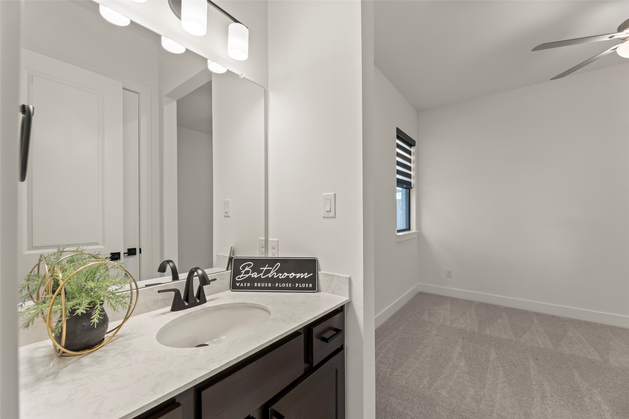 Cozy, carpeted bedroom featuring a stylish ceiling fan and ample natural light.