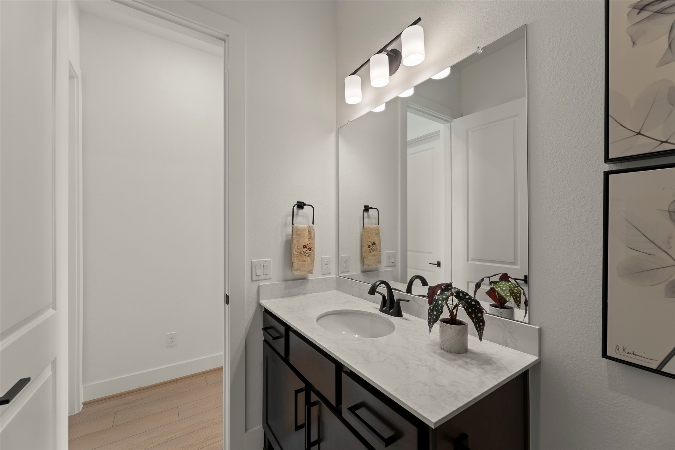 Modern bathroom with a sleek marble countertop, stylish black fixtures, and ample lighting.