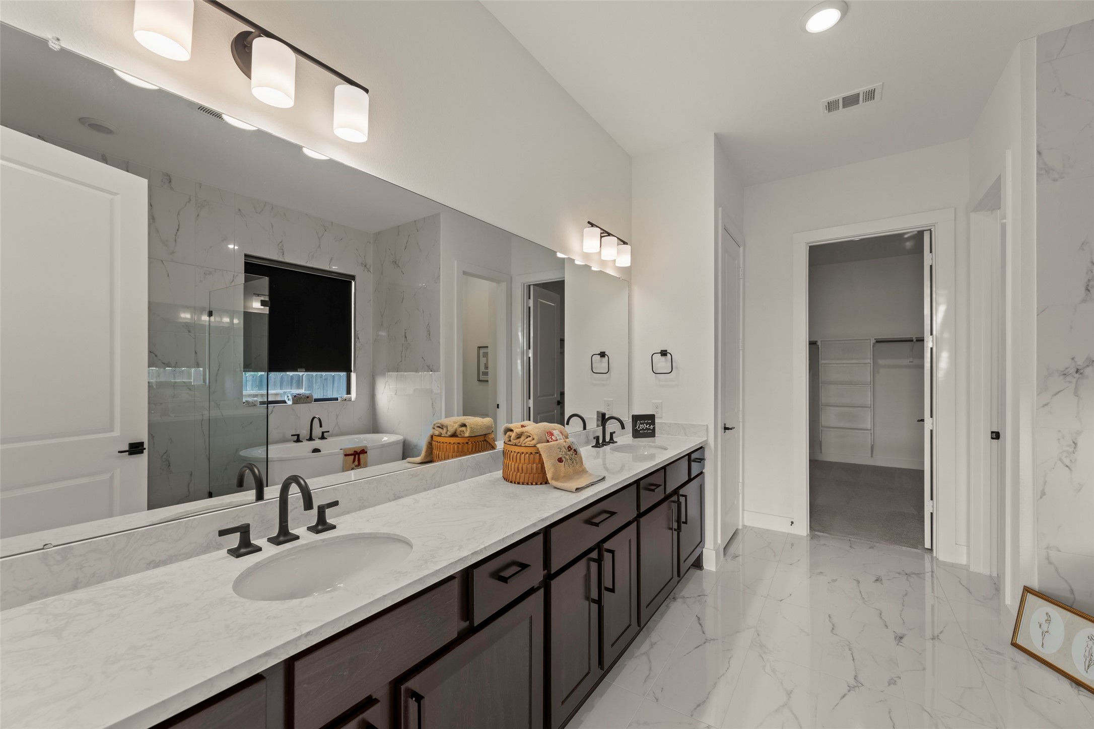 Luxurious bathroom featuring a dual-sink vanity with elegant marble countertops, modern fixtures, and a spacious walk-in closet.