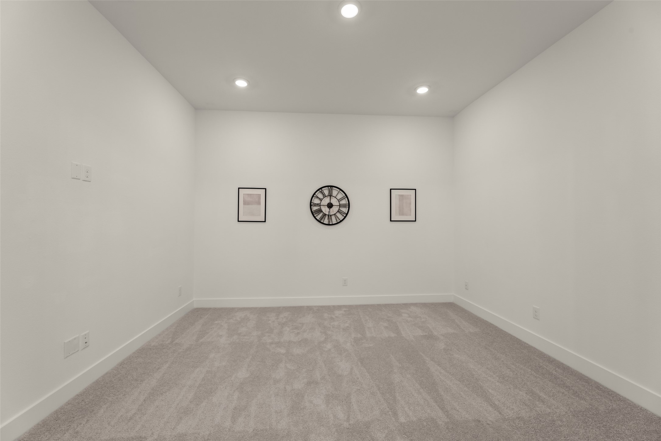 Versatile room with soft carpeting and recessed lighting, ideal for a home office or media room.