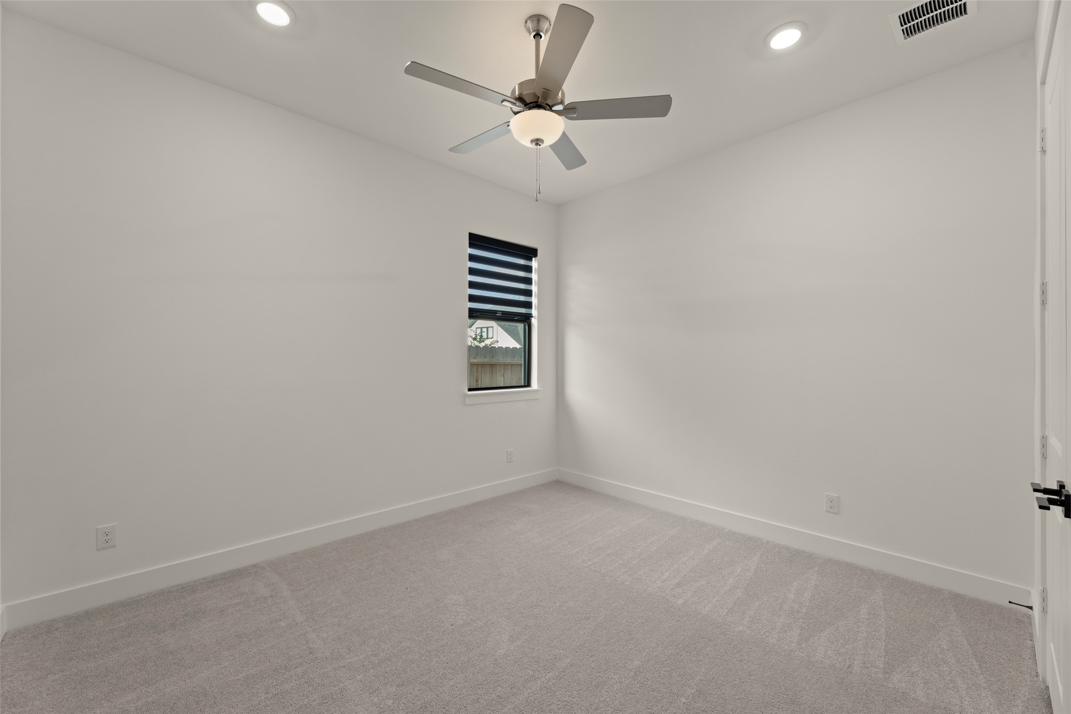 Bedroom featuring fresh carpeting, a modern ceiling fan, and recessed lighting, complemented by a window with sleek blinds.