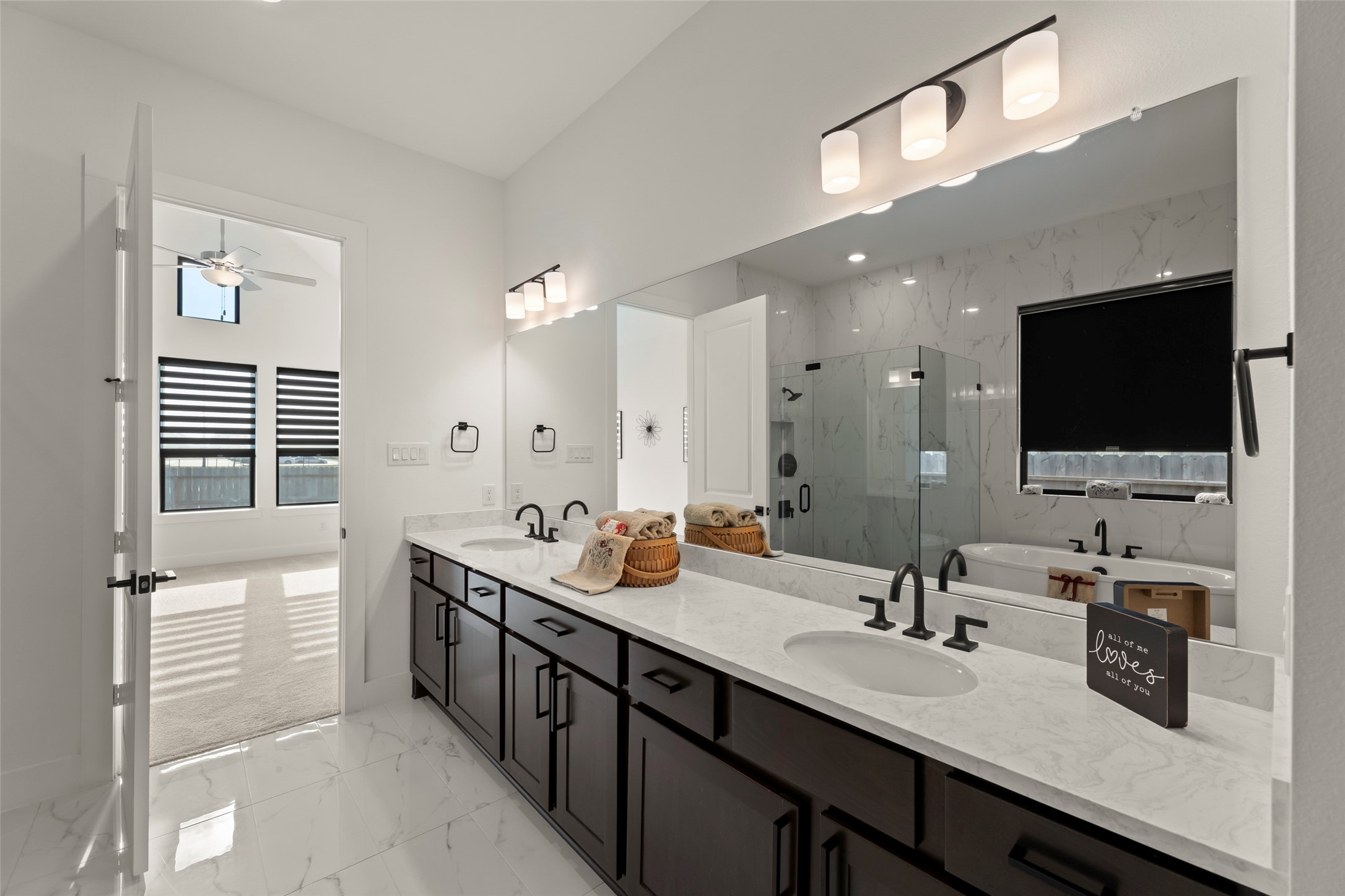 Luxurious bathroom featuring a double vanity with elegant fixtures, a spacious glass-enclosed shower, and a relaxing soaking tub, all complemented by modern lighting and sleek tile flooring.