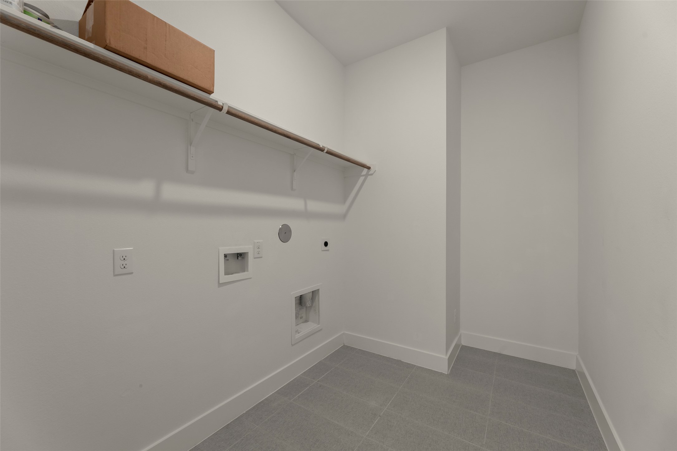 Laundry room with tile flooring, ample shelving, and washer/dryer hookups, perfect for organization and convenience.