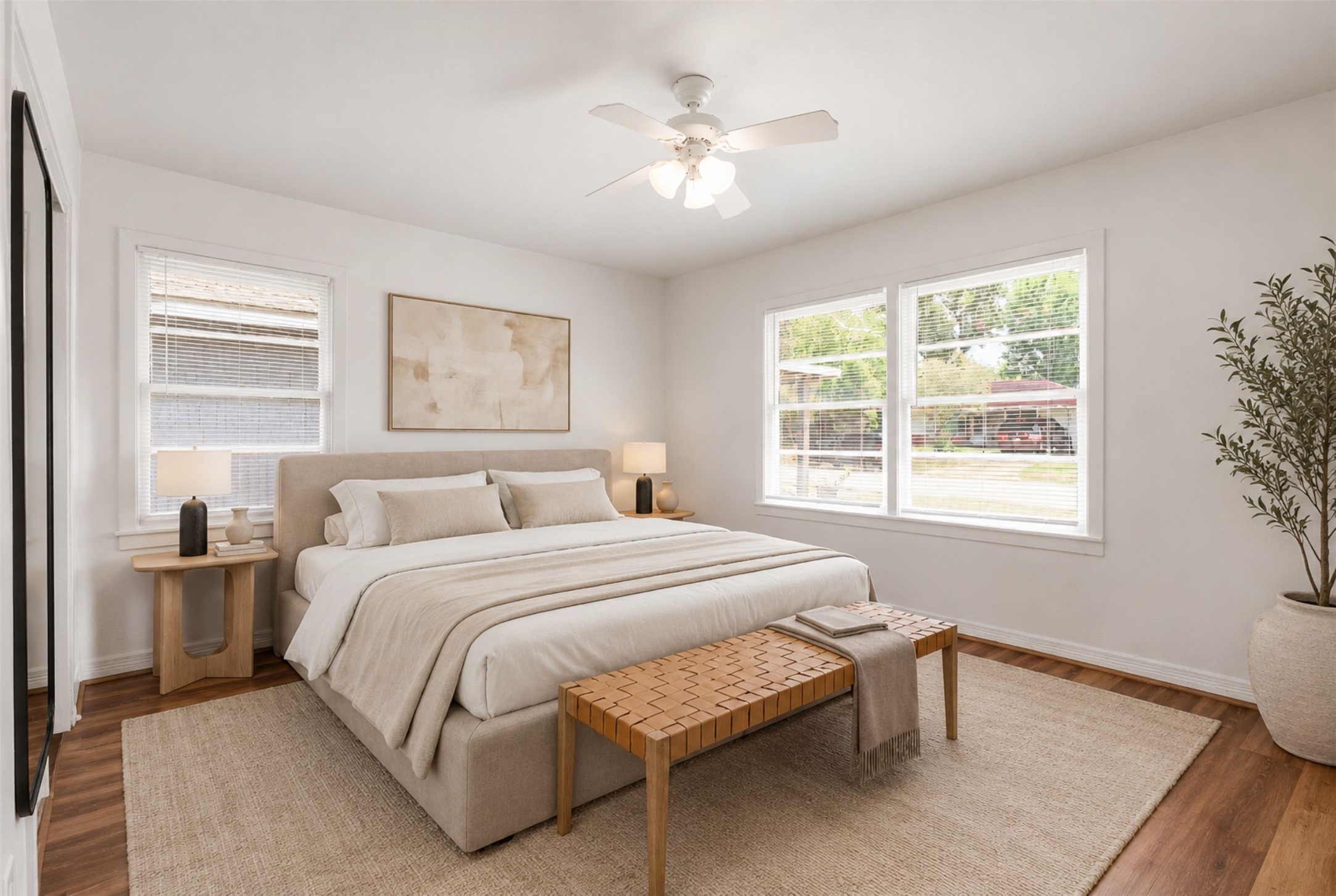 Experience serene comfort in this bedroom, featuring abundant natural light, warm wood flooring, and elegant furnishings that create a peaceful retreat. (Virtual Staging)